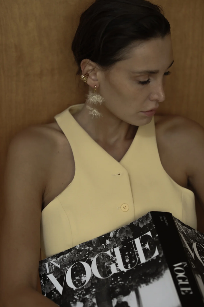 Soft golden flowers bloom along fine gold chain strands, creating a warm, glowing cascade of color and movement. Designed to catch the light with every turn, their delicate golden hues and intricate floral details evoke a sense of sophistication and effor