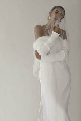 Model bride wearing strapless wedding dress with drop veil and pearl earrings