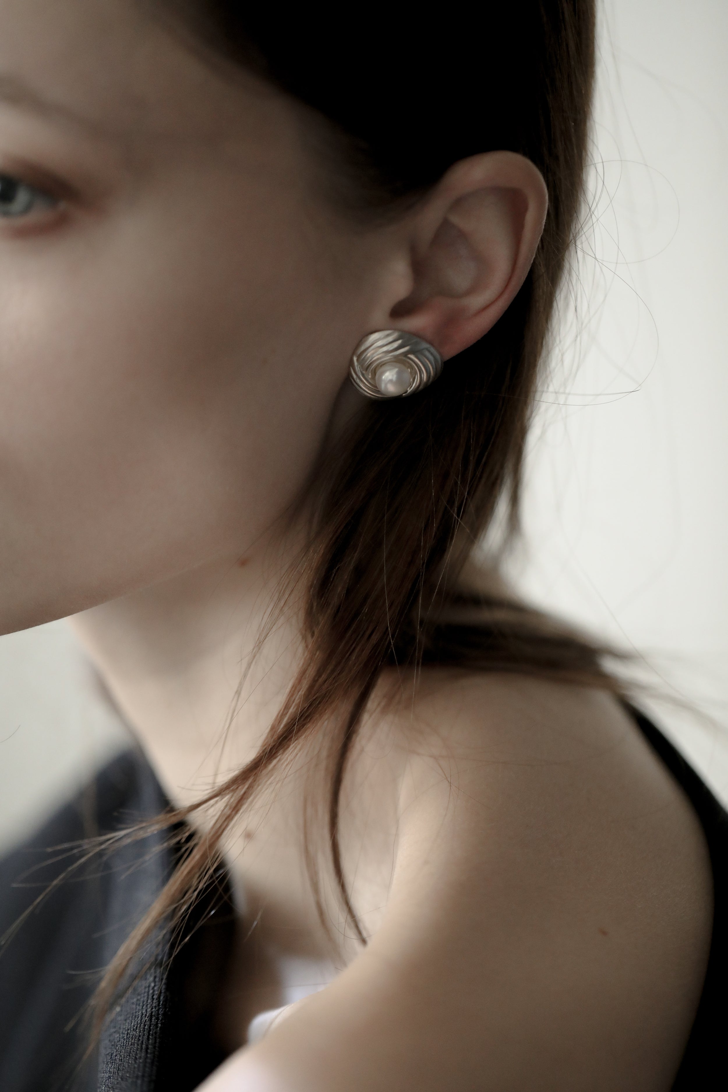 Close up photo of brunette woman wearing the sterling silver ribbed pearl earrings by AB Ellie