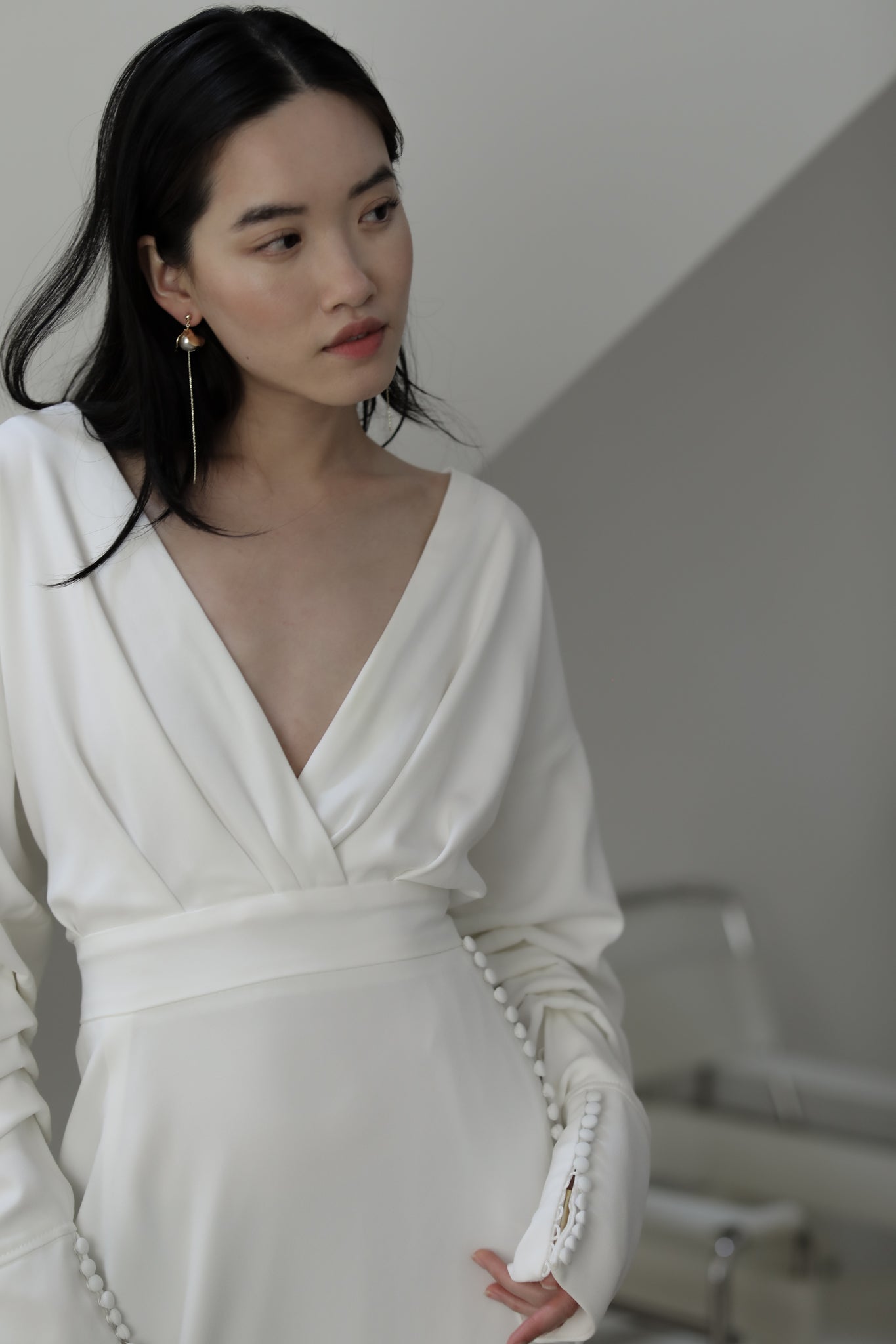 Dark hared bride wearing the Bardot pearl strand earrings by AB Ellie with modern wedding dress