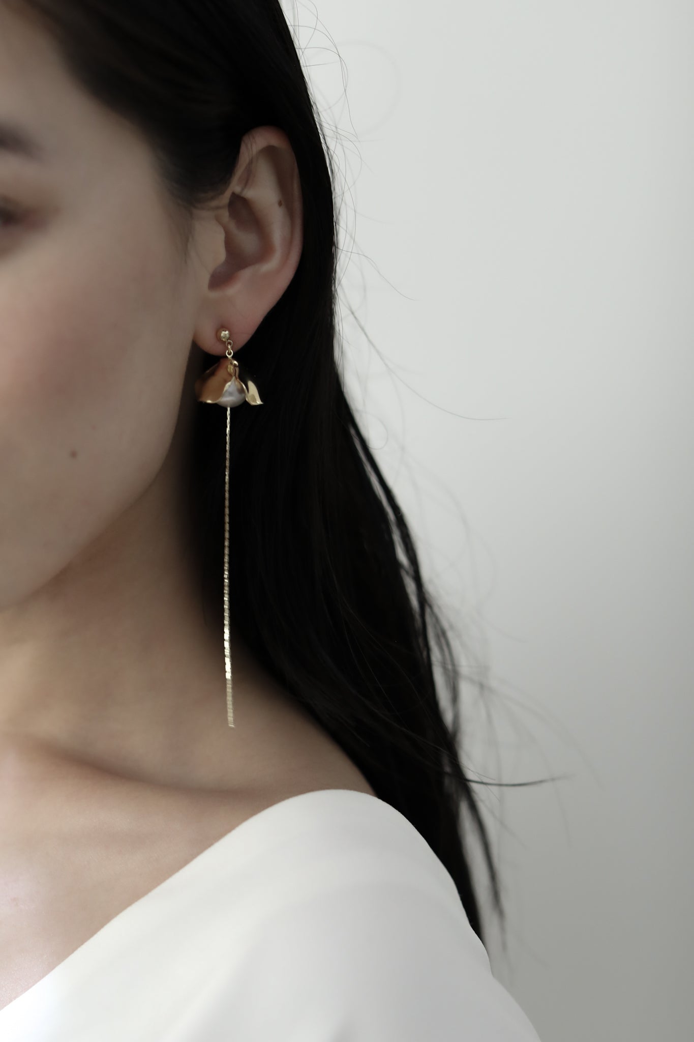 Side view of dark haired bride wearing the Bardot pearl gold strand earring by AB Ellie