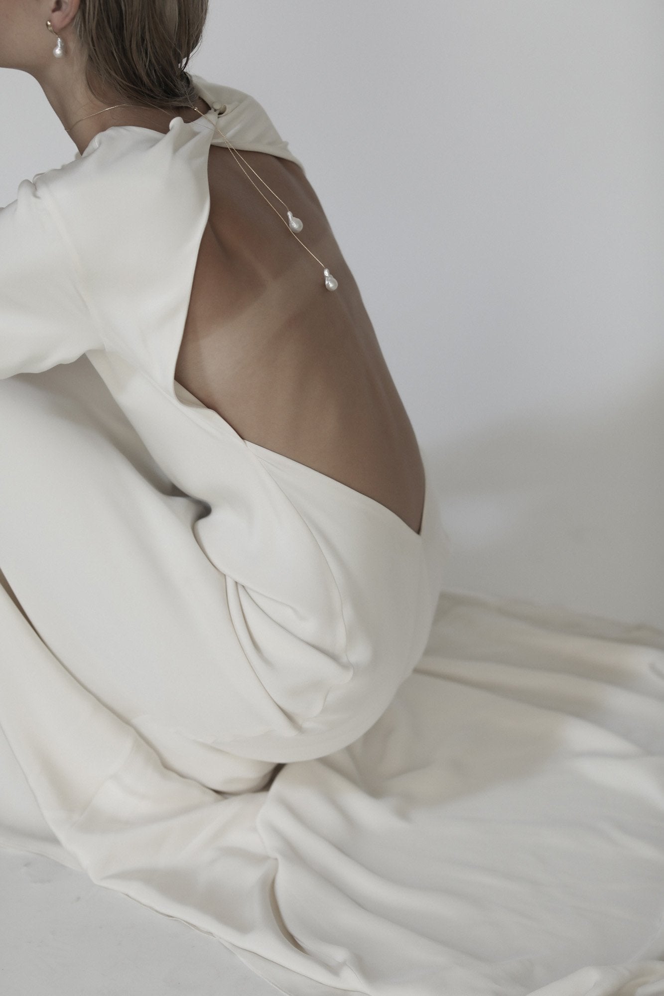 Side view of blonde bride wearing the baroque pearl lariat necklace by AB Ellie with an open back wedding dress
