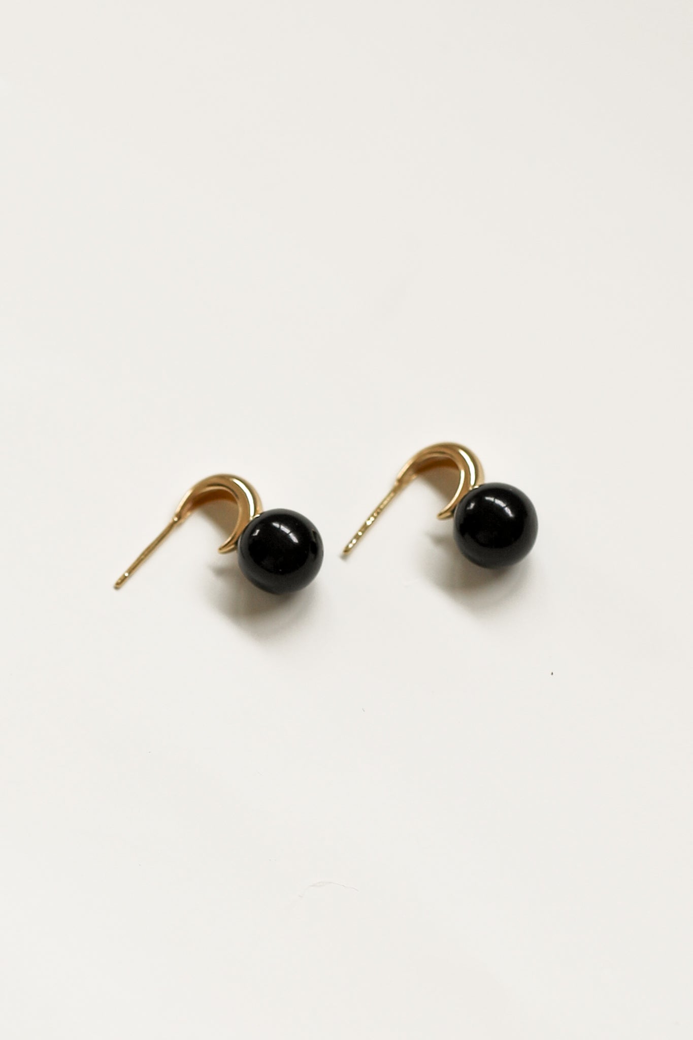 Flat image of gold crescent hoop earrings with lack onyx drop by A.B. Ellie on white background