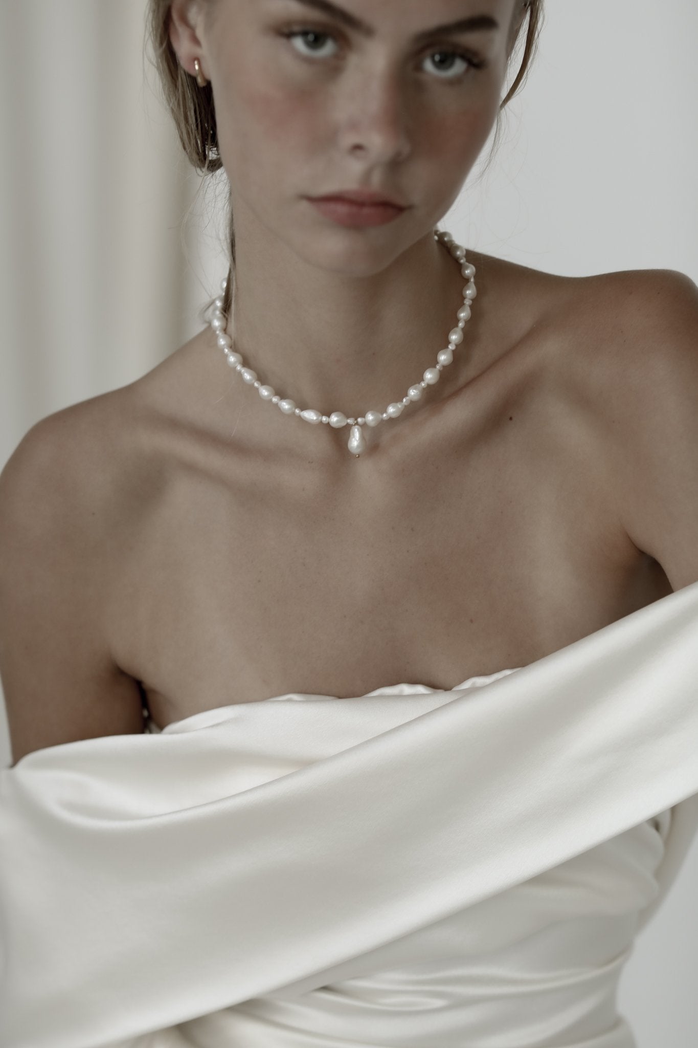 Front view of bride wearing the demi freshwater pearl necklace by AB Ellie paired with an off-the-shoulder wedding dress.
