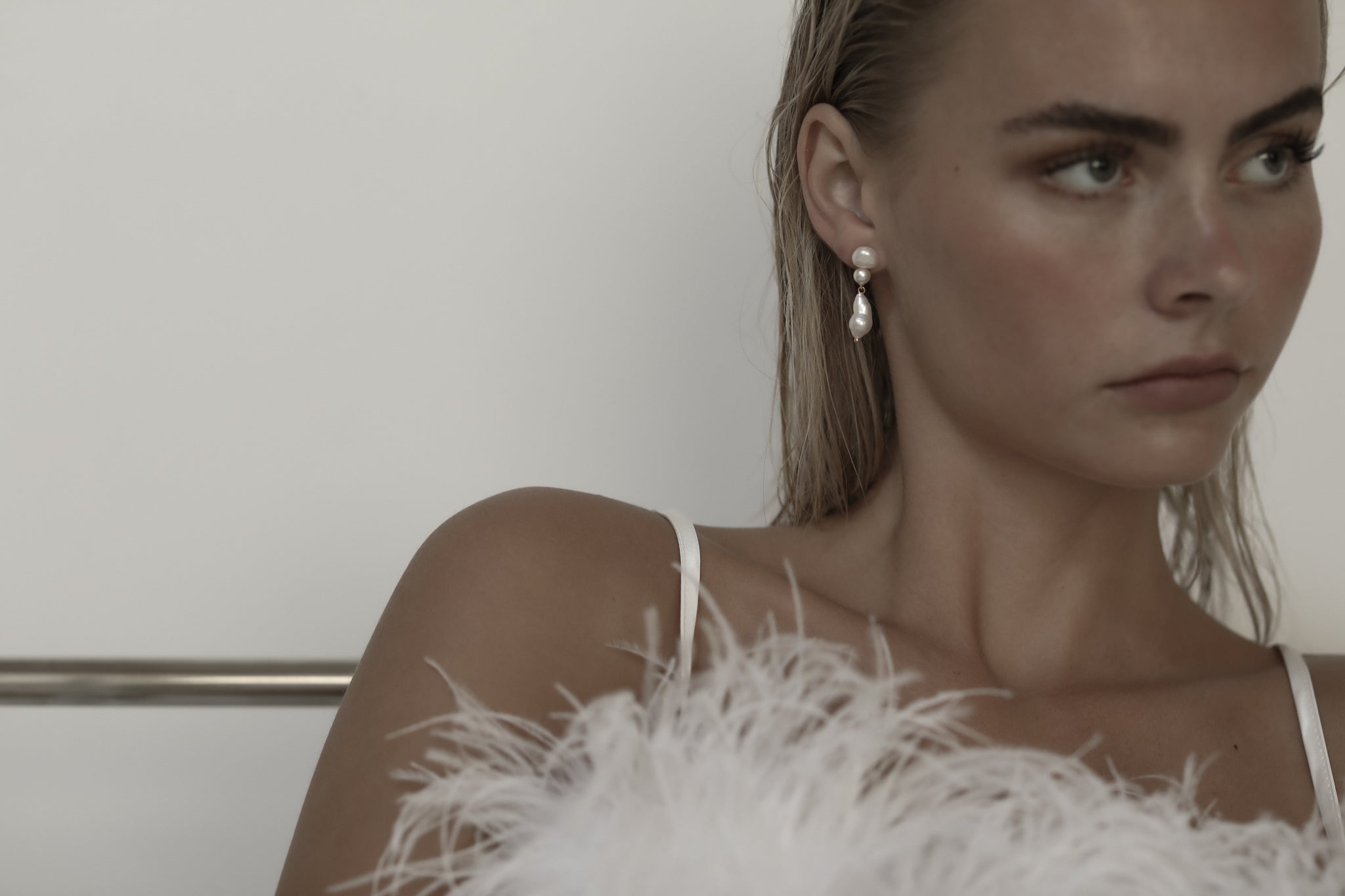 Blonde model wearing Freshwater pearl drop earrings with a feathered wedding gown