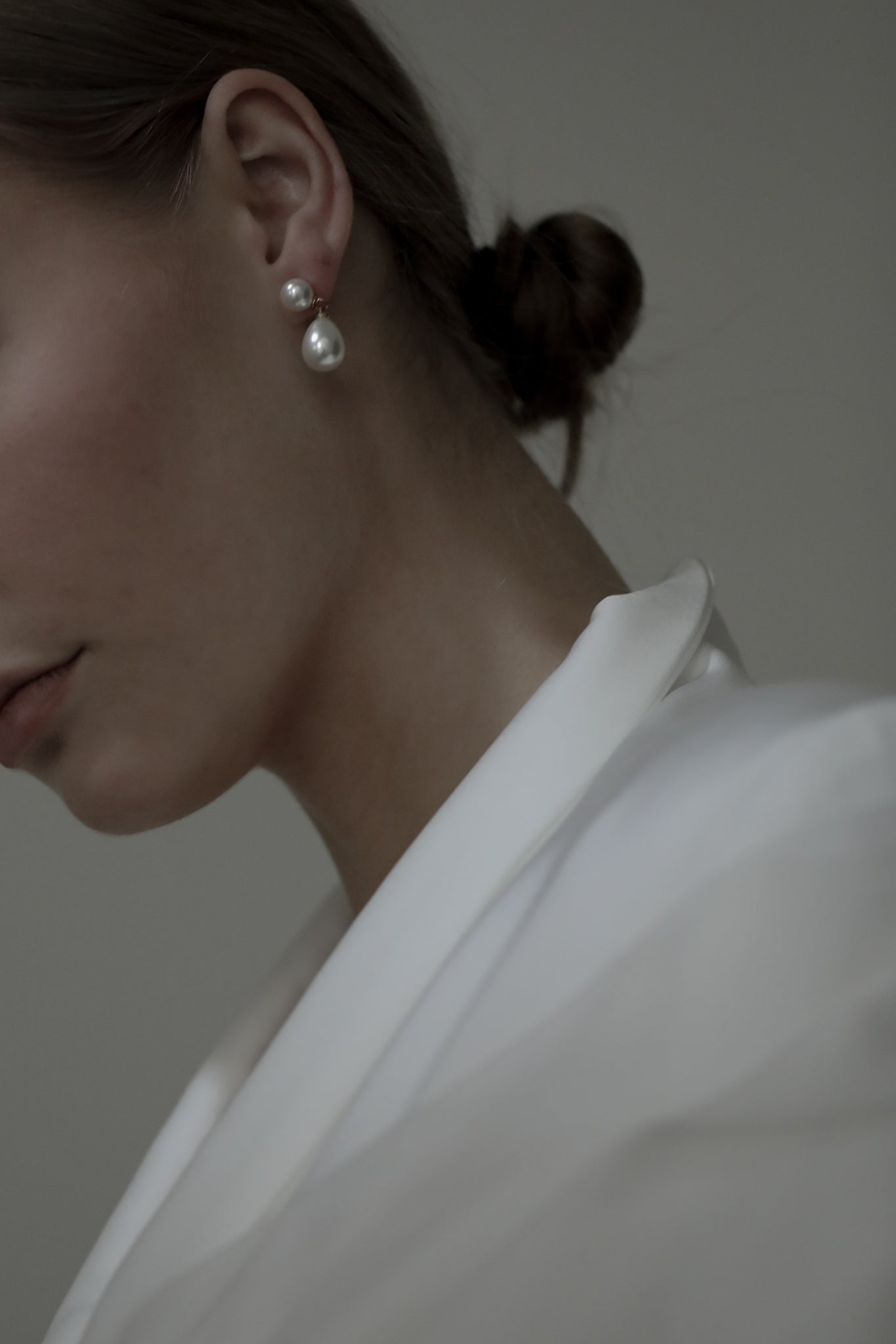 Brunette model wearing bridal suit with double pearl drop earrings