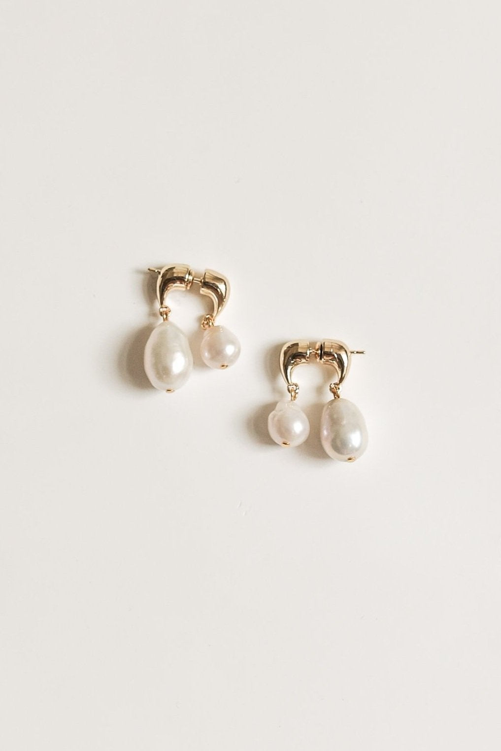 Photo of a pair of the Asymmetric orb pearl drop earrings by AB Ellie on white background