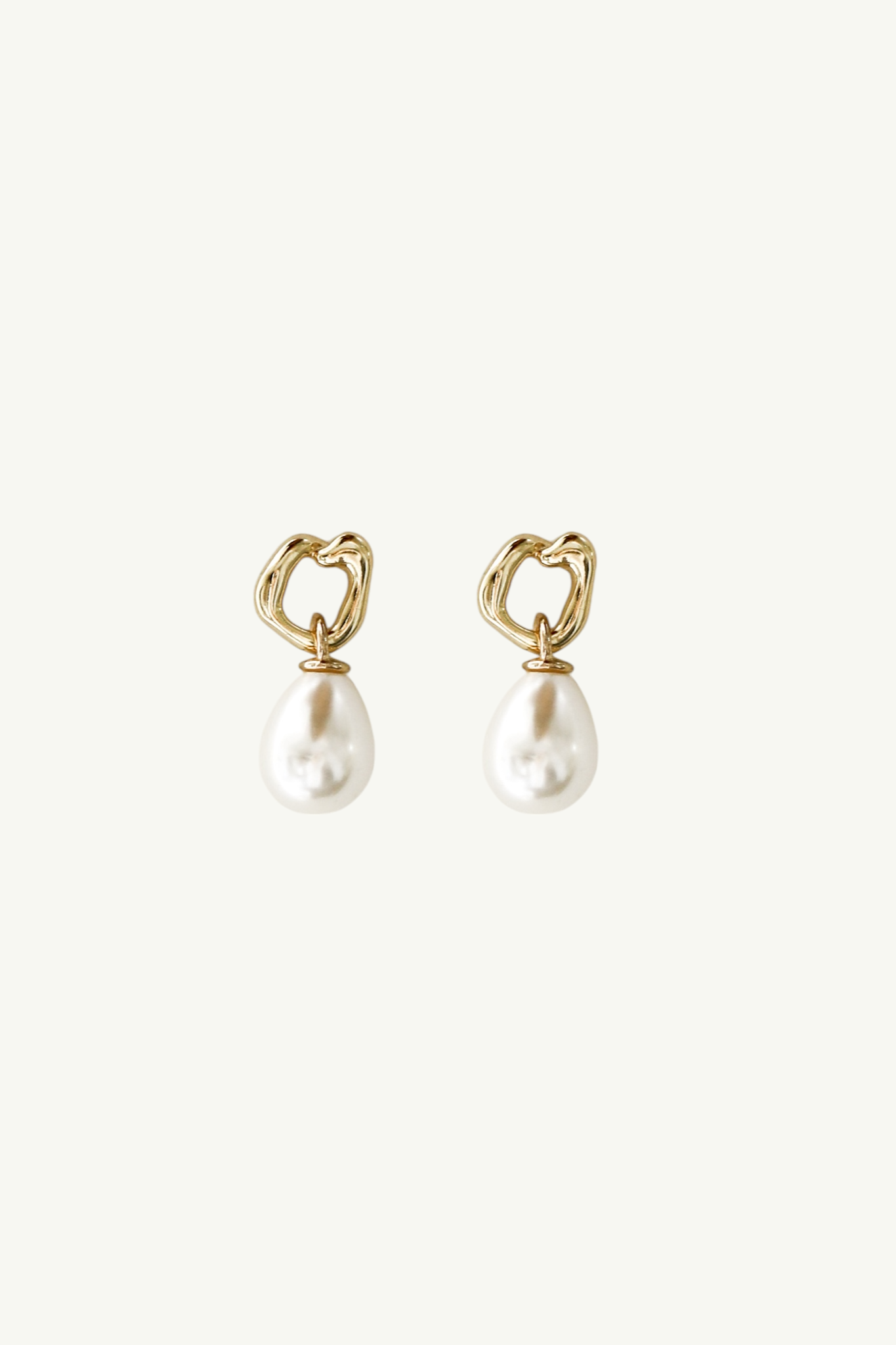 Flat image on white background of irregular gilded gold hoop earrings with a classic pearl drop earring accent