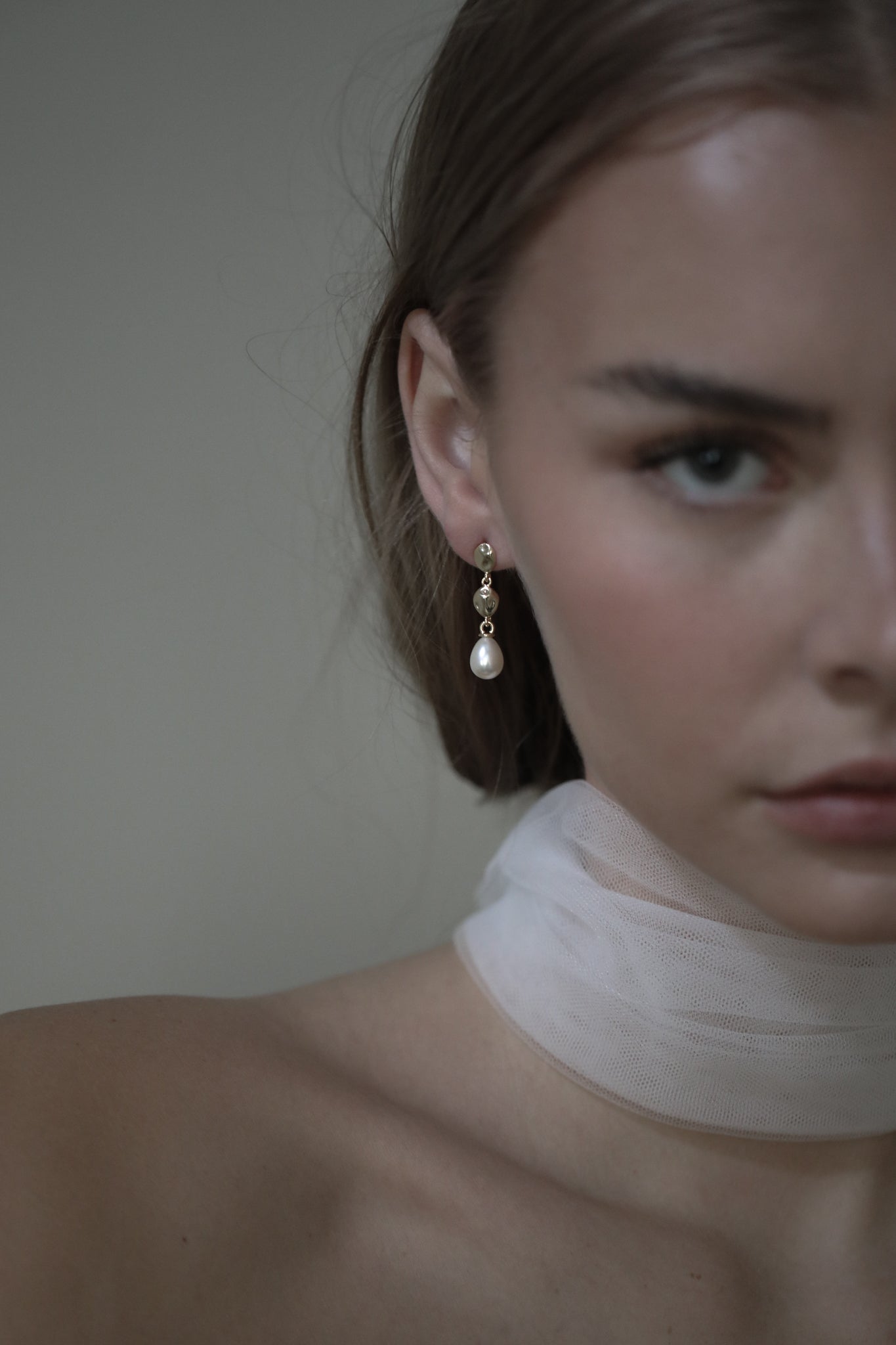 Shoulder up view of bride wearing a silk scarf paired with the gold gilded tier drop earrings with a pearl drop earring accent