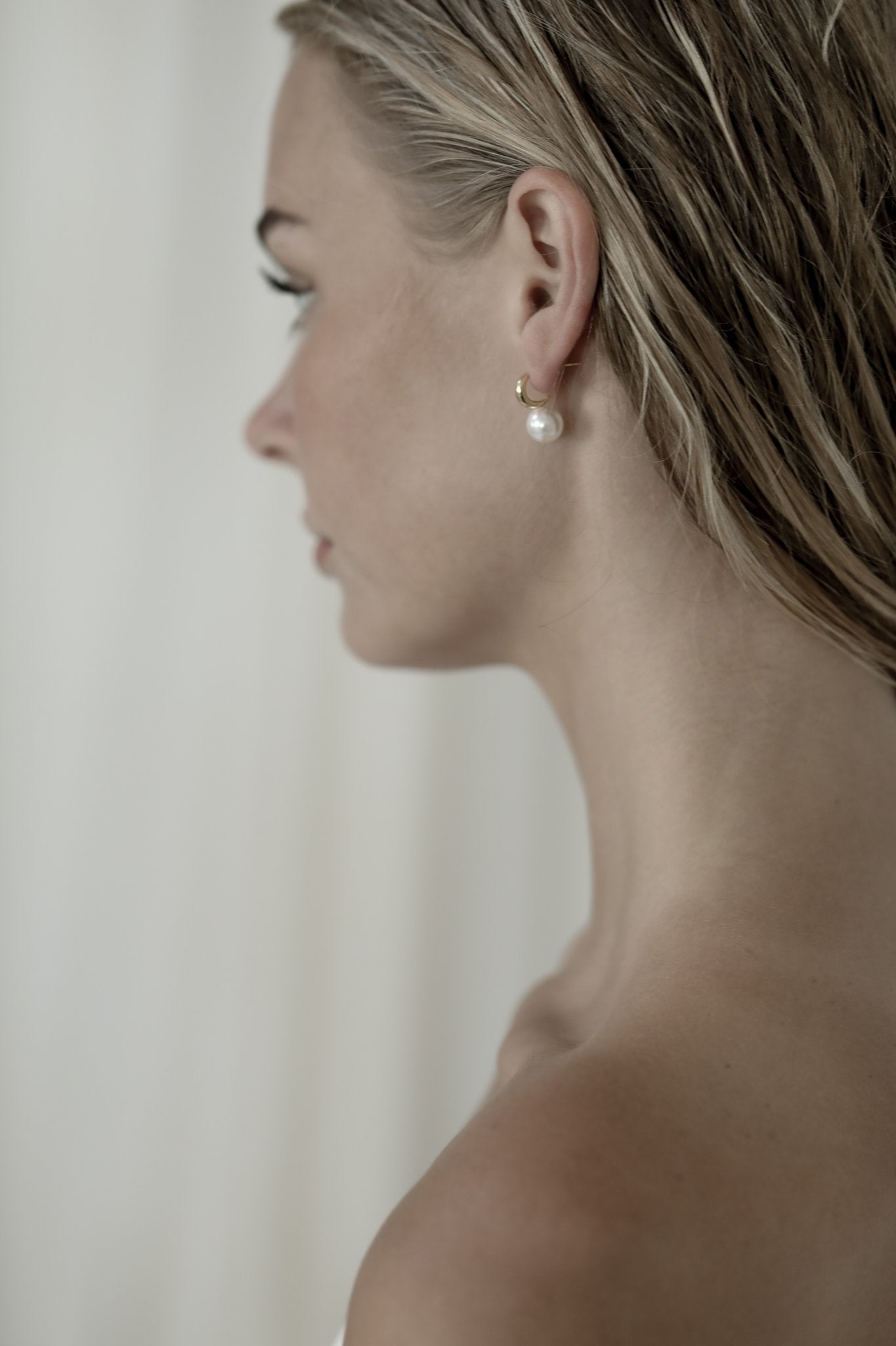 Side view of blonde bride wearing the gold crescent hoop pearl earrings by AB Ellie