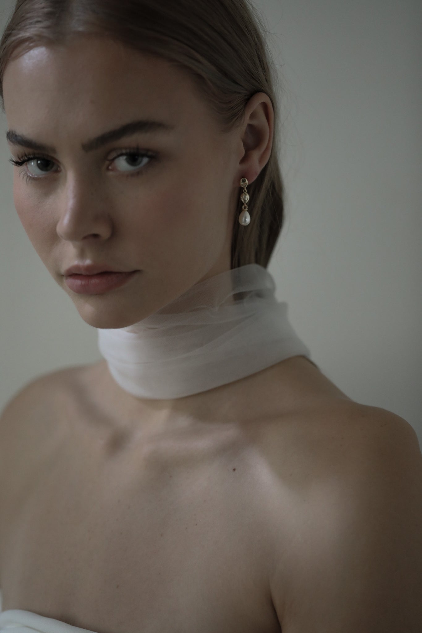 Shoulder and above view of bride wearing silk scarf paired with the gold gilded pearl drop earrings