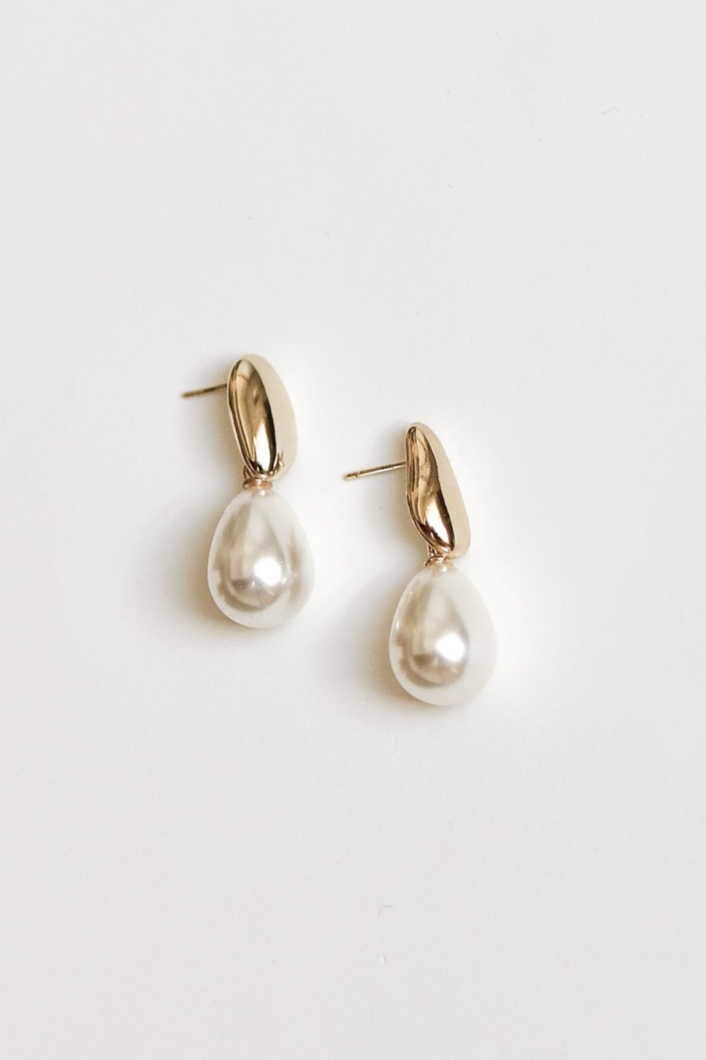 Pair of pearl drop earrings with gold accents by AB Ellie on a white background