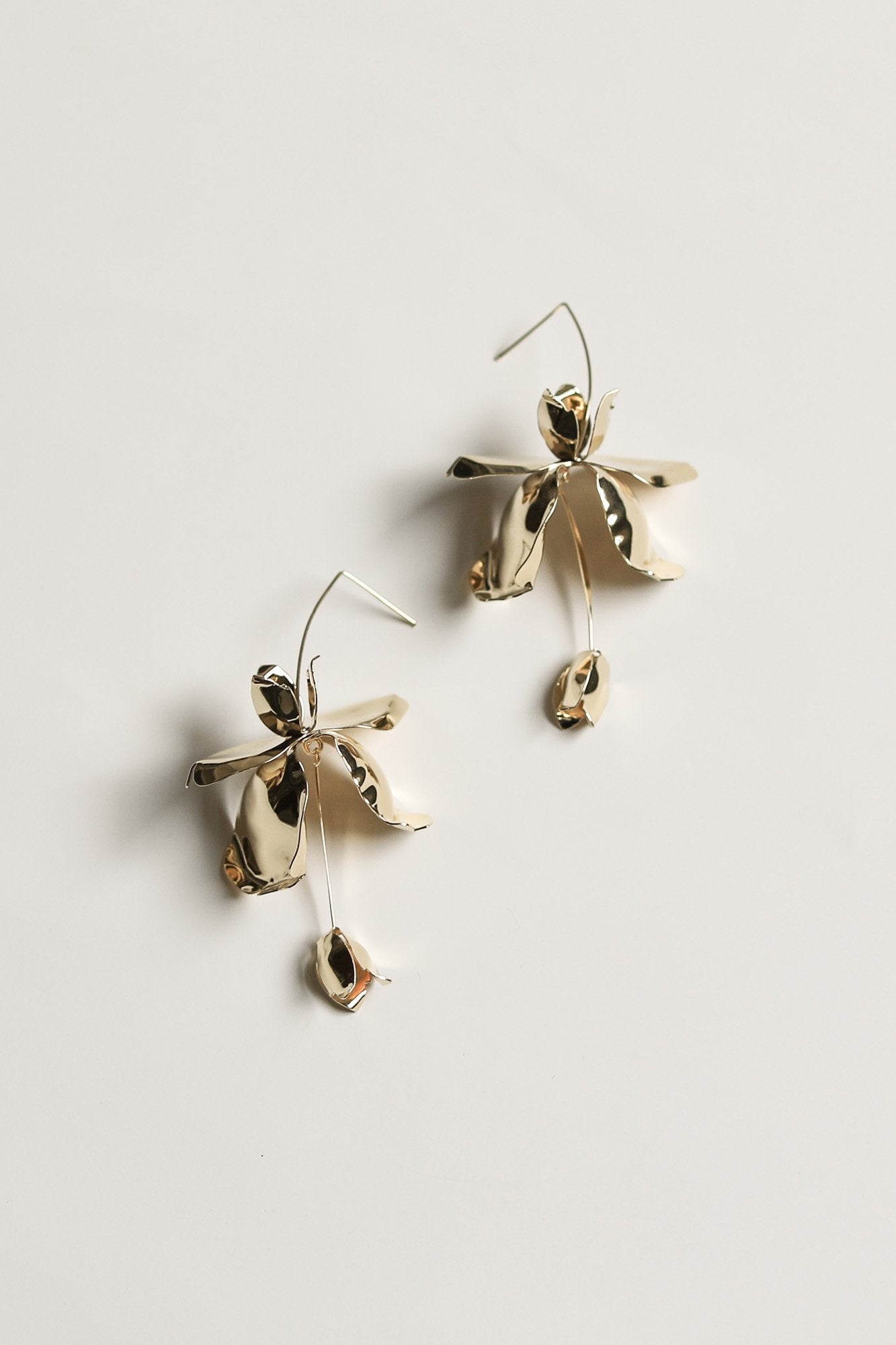 Flat photo of the gold magnolia stem drop earrings by AB Ellie on white background