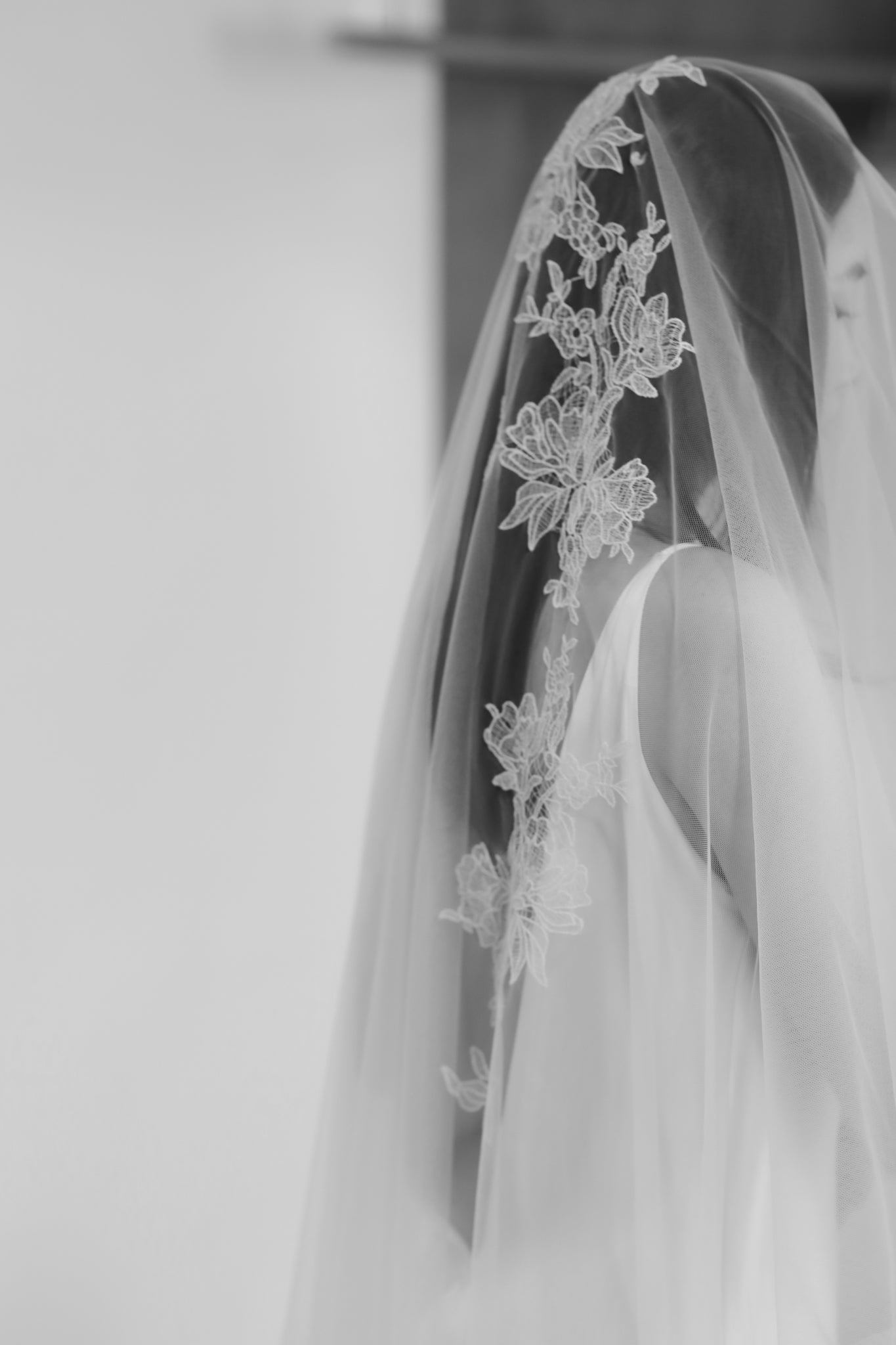 Close-up of a wedding veil with floral lace details on a plain background