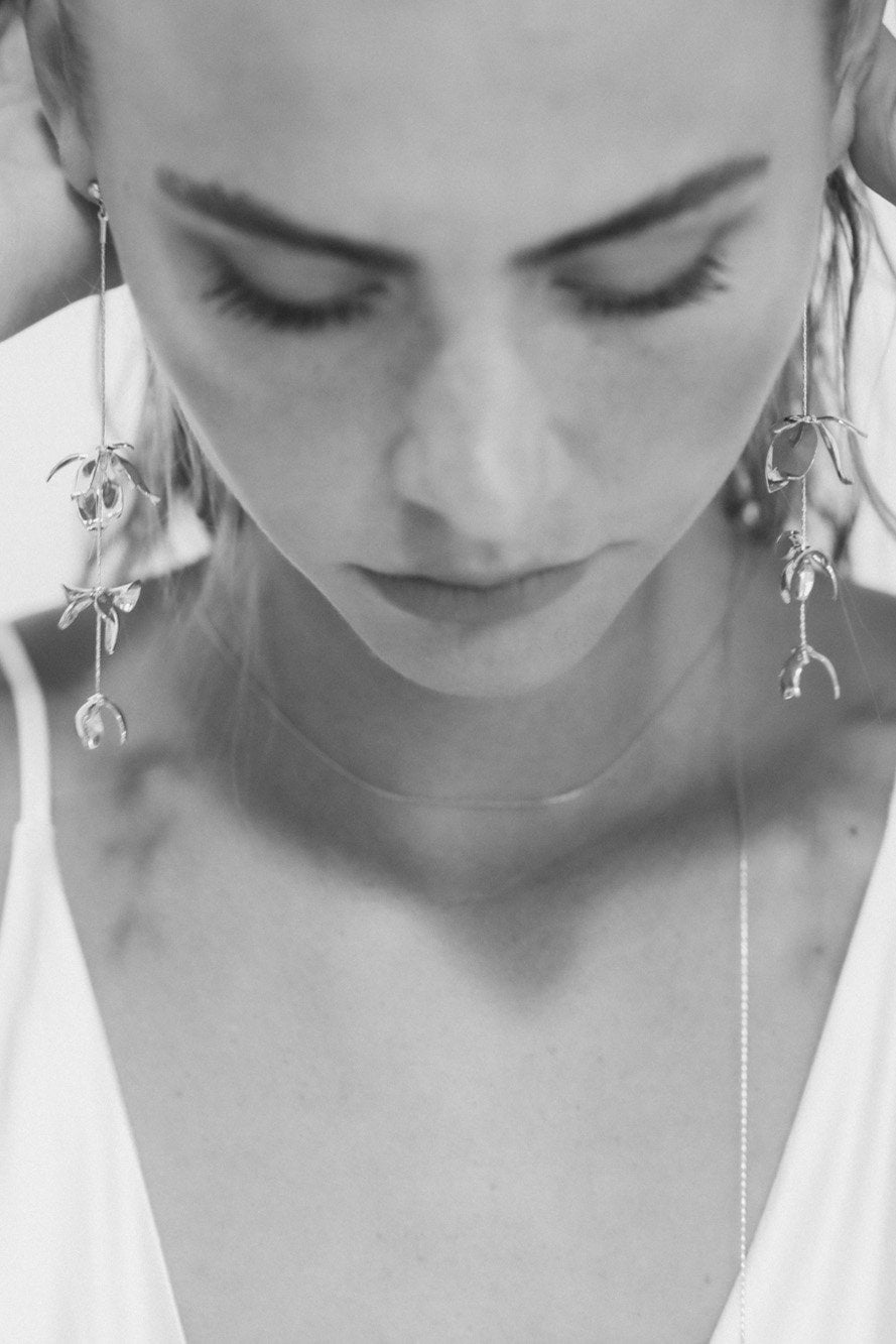 Black and white front view image of bride wearing the Magnolia strand earrings