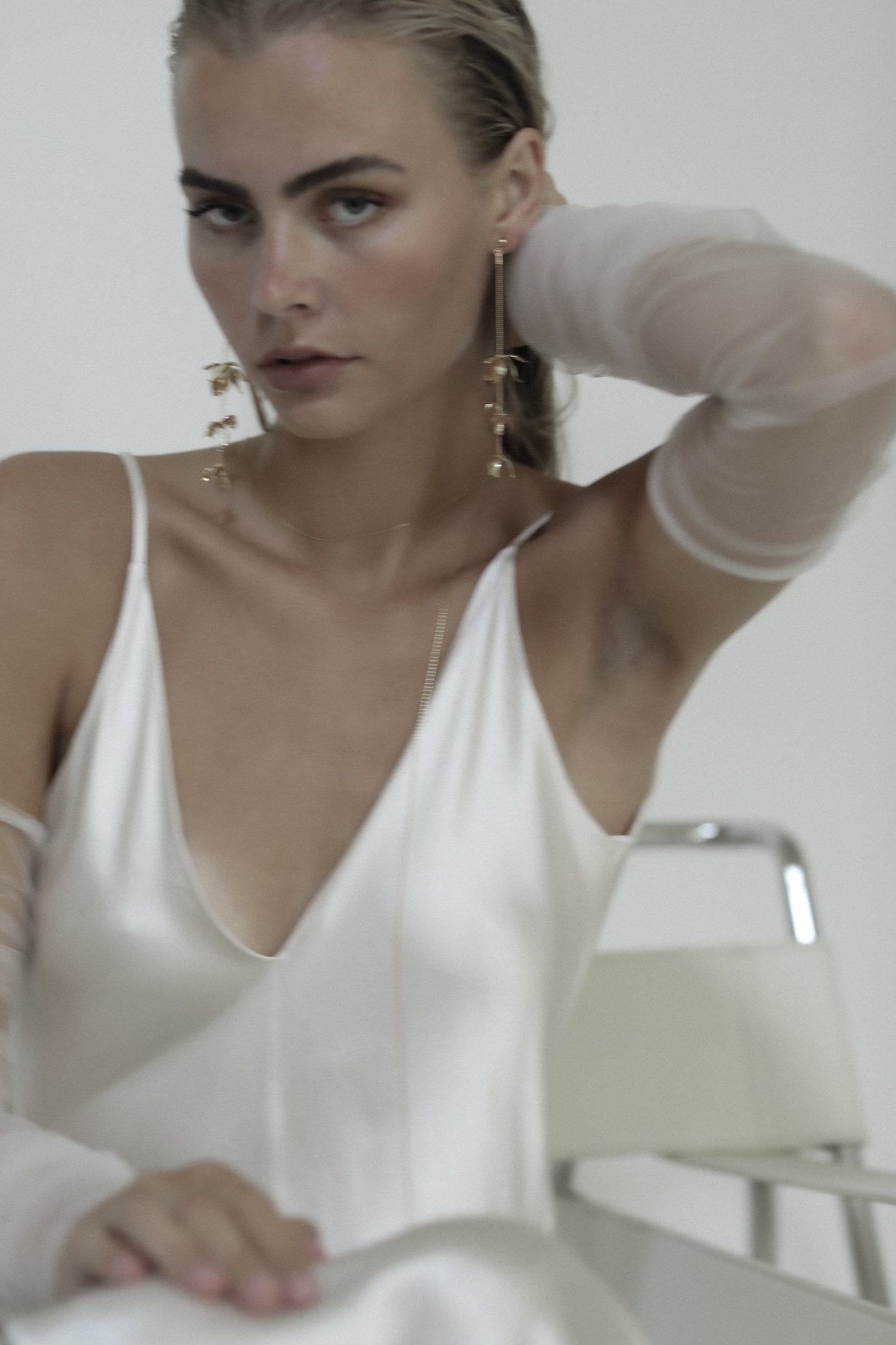 Blonde bride wearing the full length gold Magnolia strand earrings by A.B. Ellie paired with an ivory sheath dress
