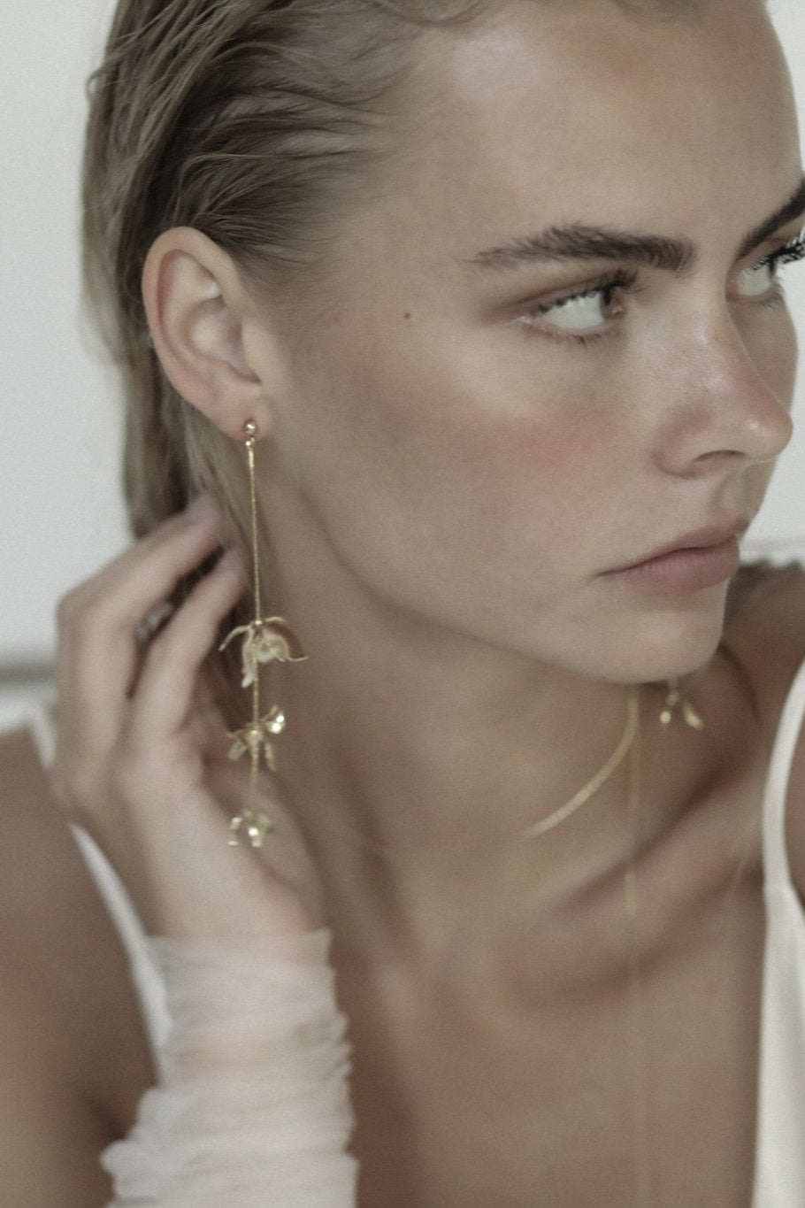 Blonde bride wearing gold Magnolia strand earrings with sleave accent and ivory dress