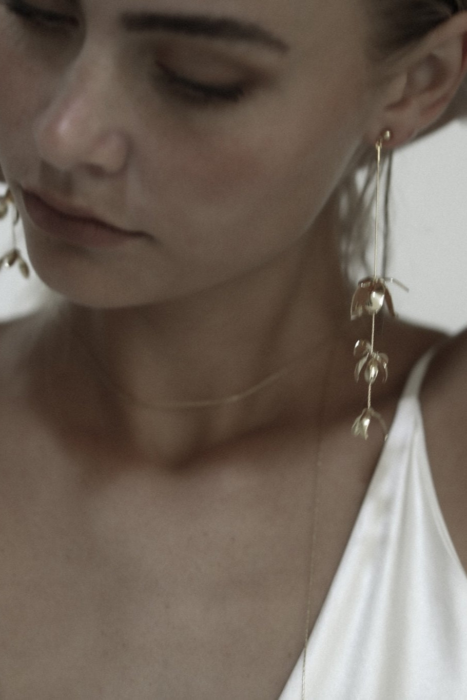 Close up front view of bride wearing gold Magnolia strand earrings by A.B. Ellie