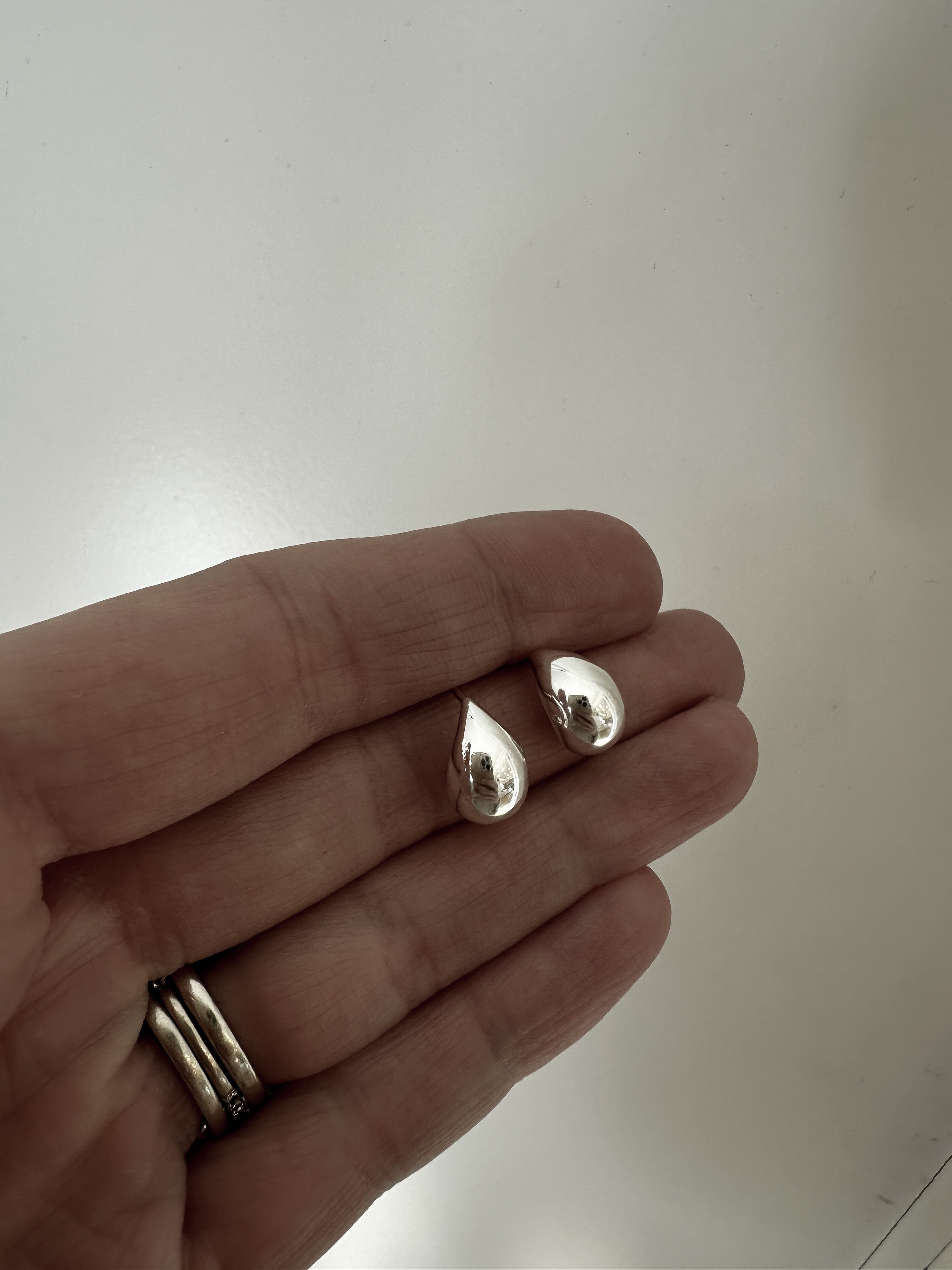 Photo of hand holding a pair of the micro orb silver earrings by AB Ellie