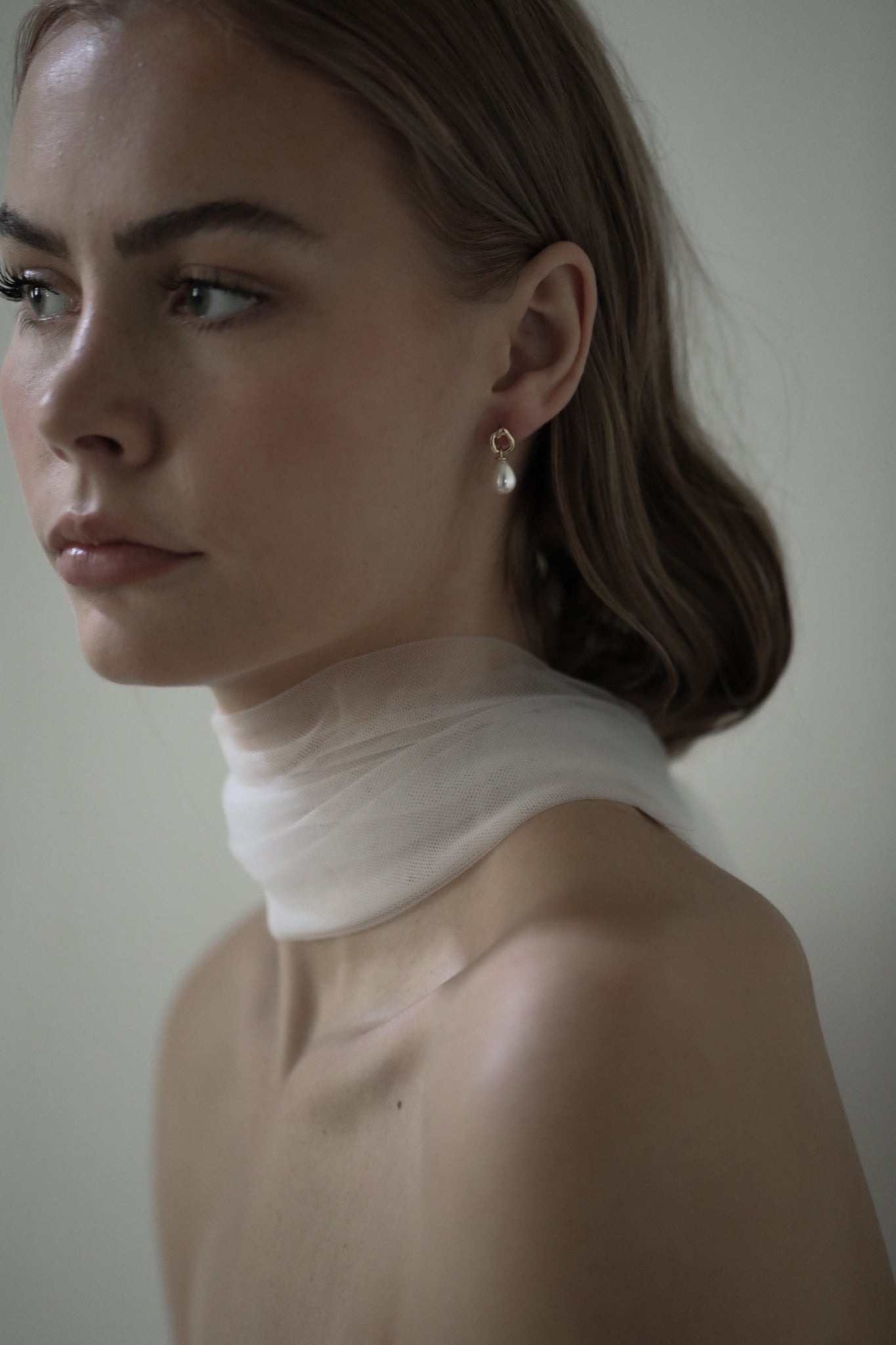 Side view of bride wearing a silk bridal scarf and gold mini hoop earrings featuring a classic pearl earring drop