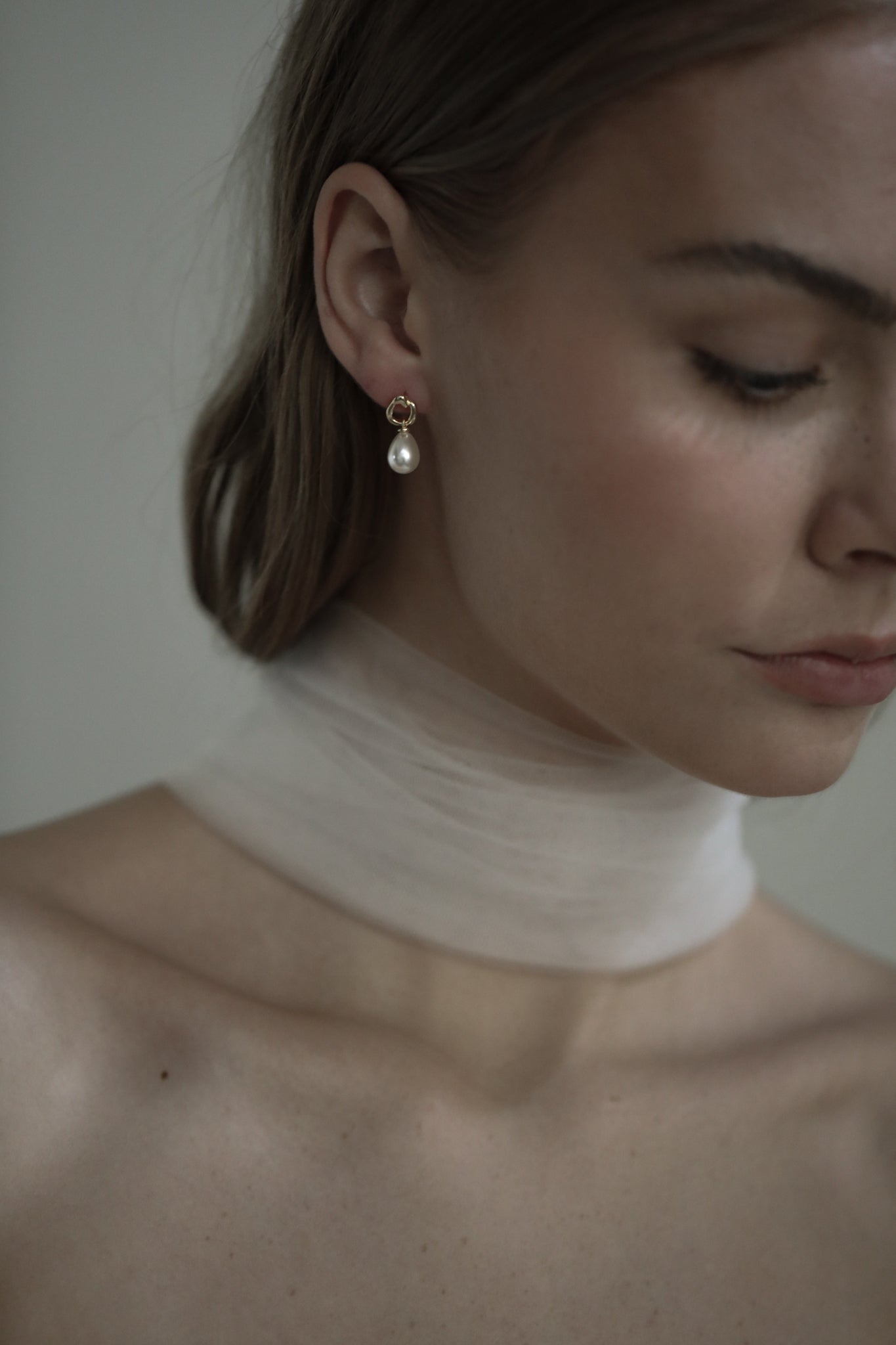 Brunette bride wearing bridal necktie and mini gold gilded hoop earring with a classic pearl drop earring accent