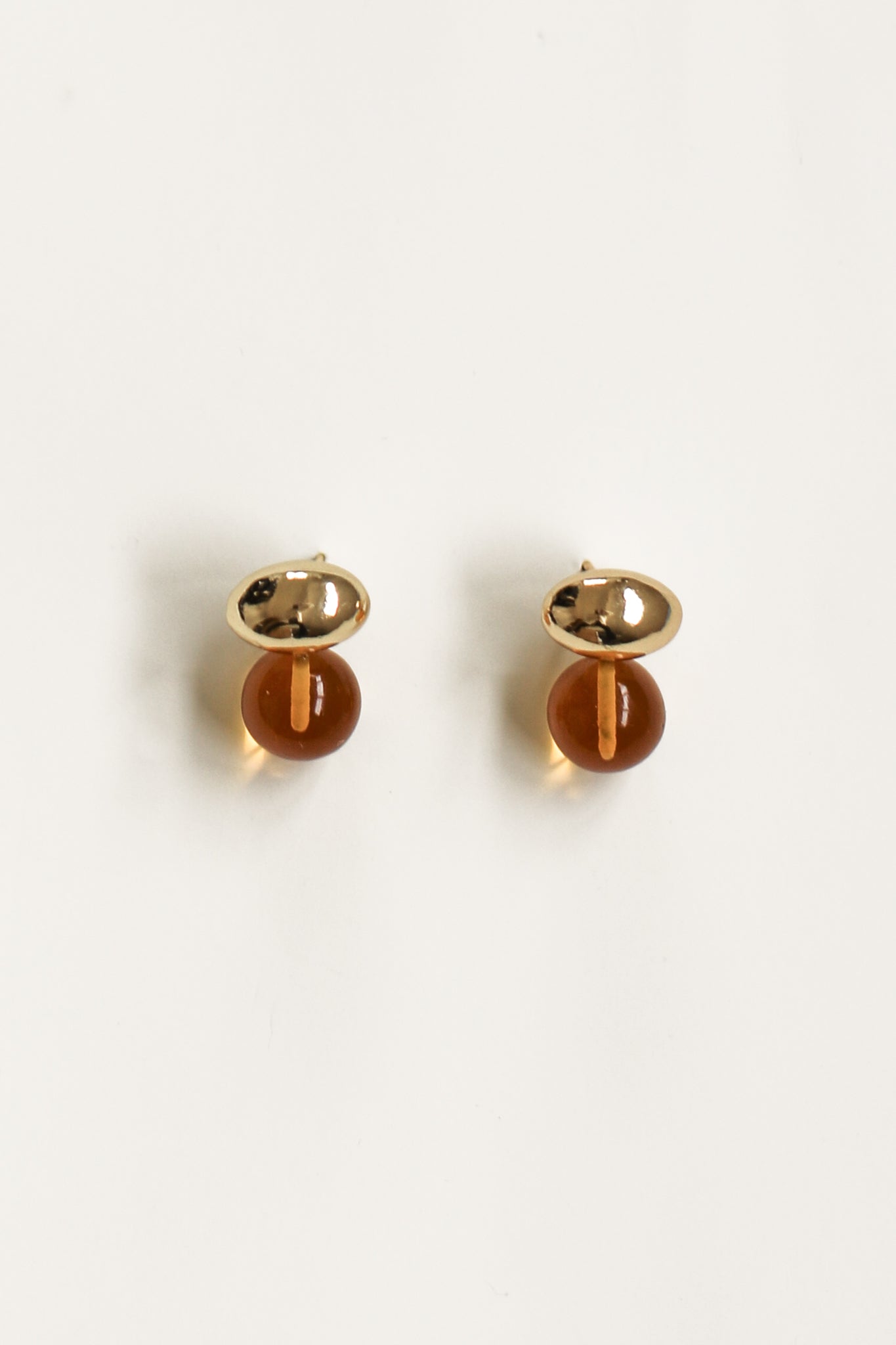 Flat image of Orb and glass drop earrings in gold and amber color by A.B. Ellie on white background