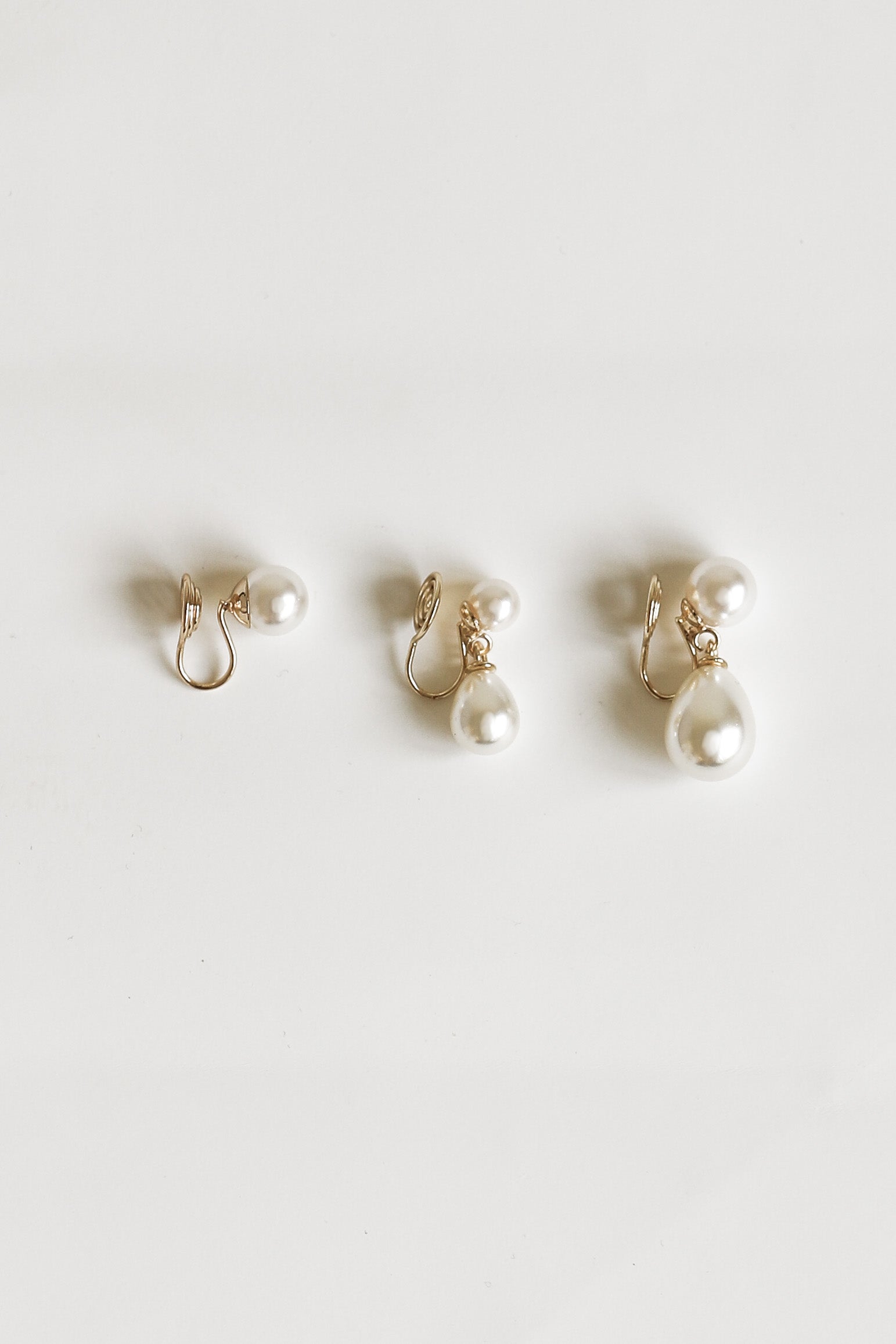 Set of three pearl clip on earrings on a white background