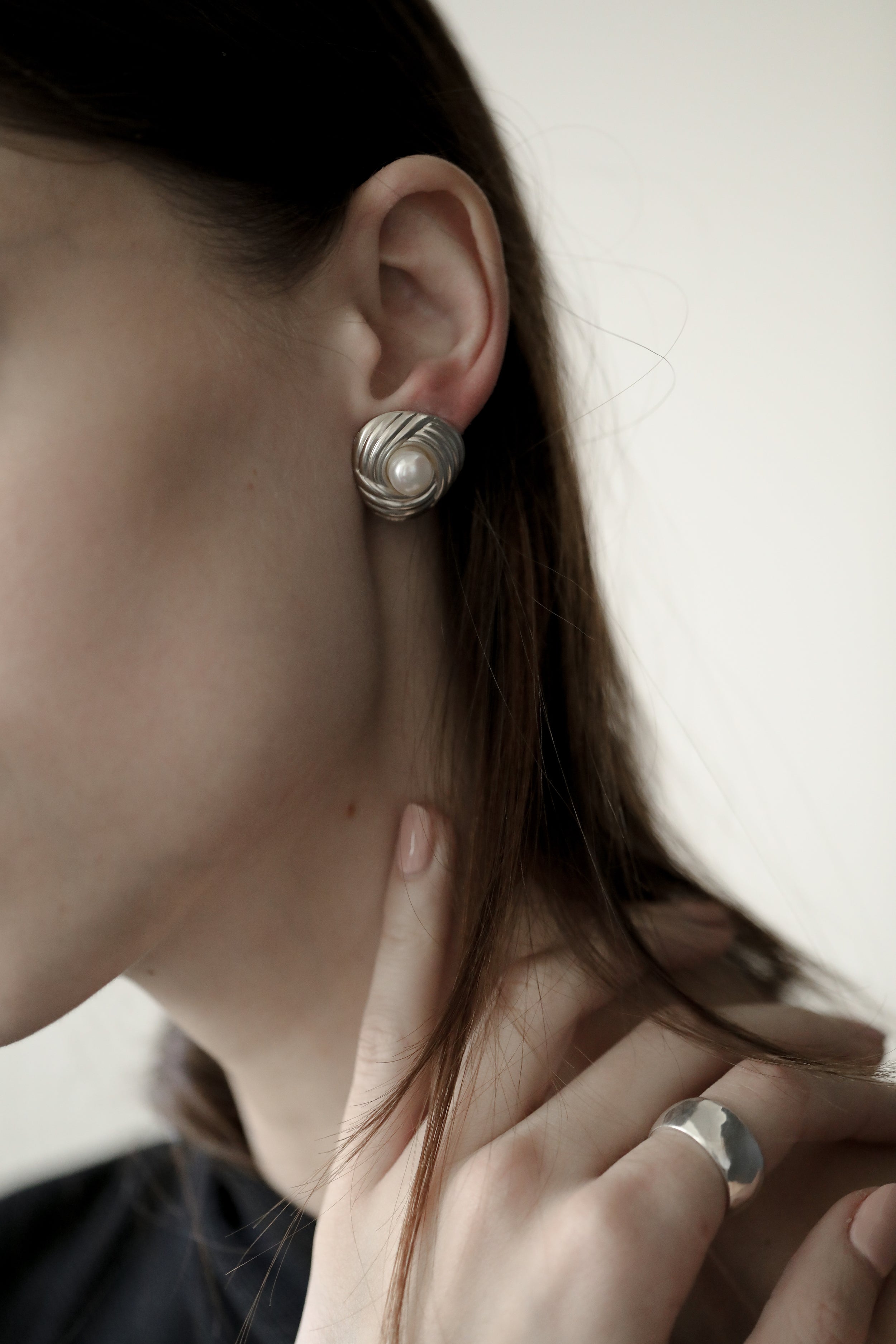 Close up photo of brunette woman wearing the ribbed pearl sterling silver stud earrings by AB Ellie