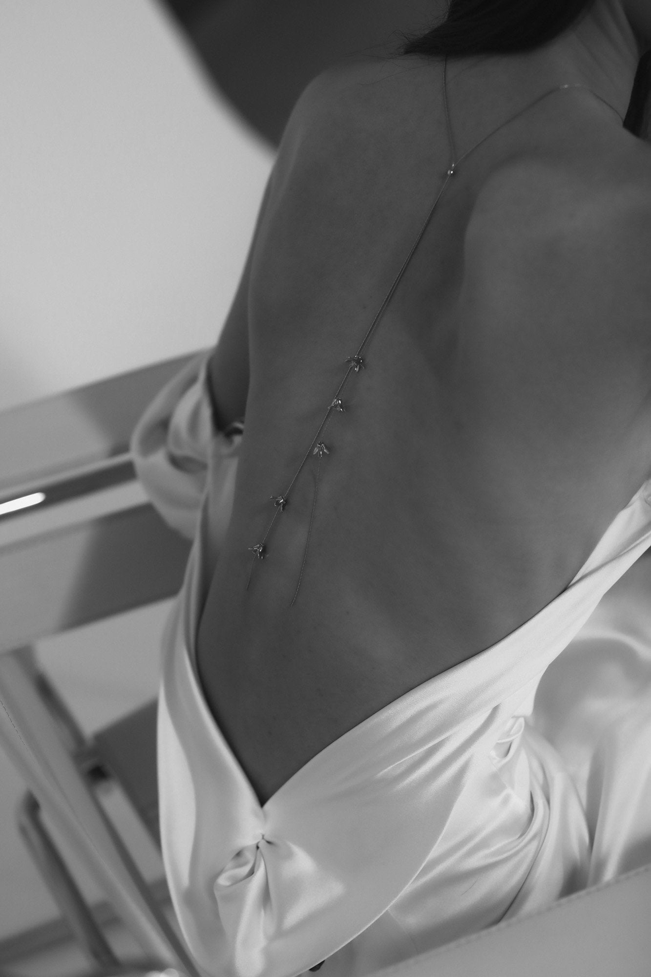 Black and white image of Rue lariat necklace by AB Ellie on bride with open back dress