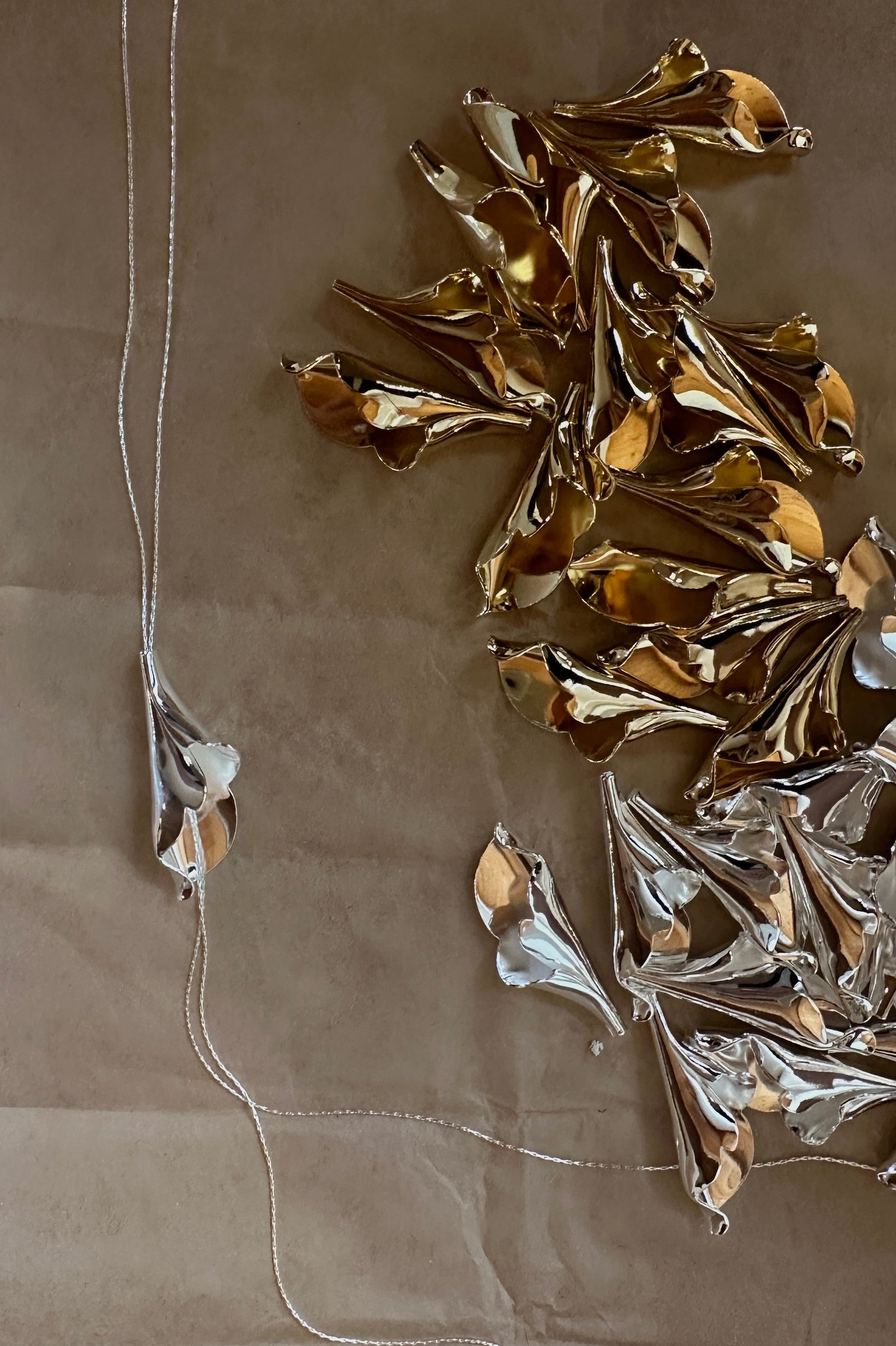Photo of silver and gold variations of the floral Tula lariat necklace by AB Ellie on kraft paper background