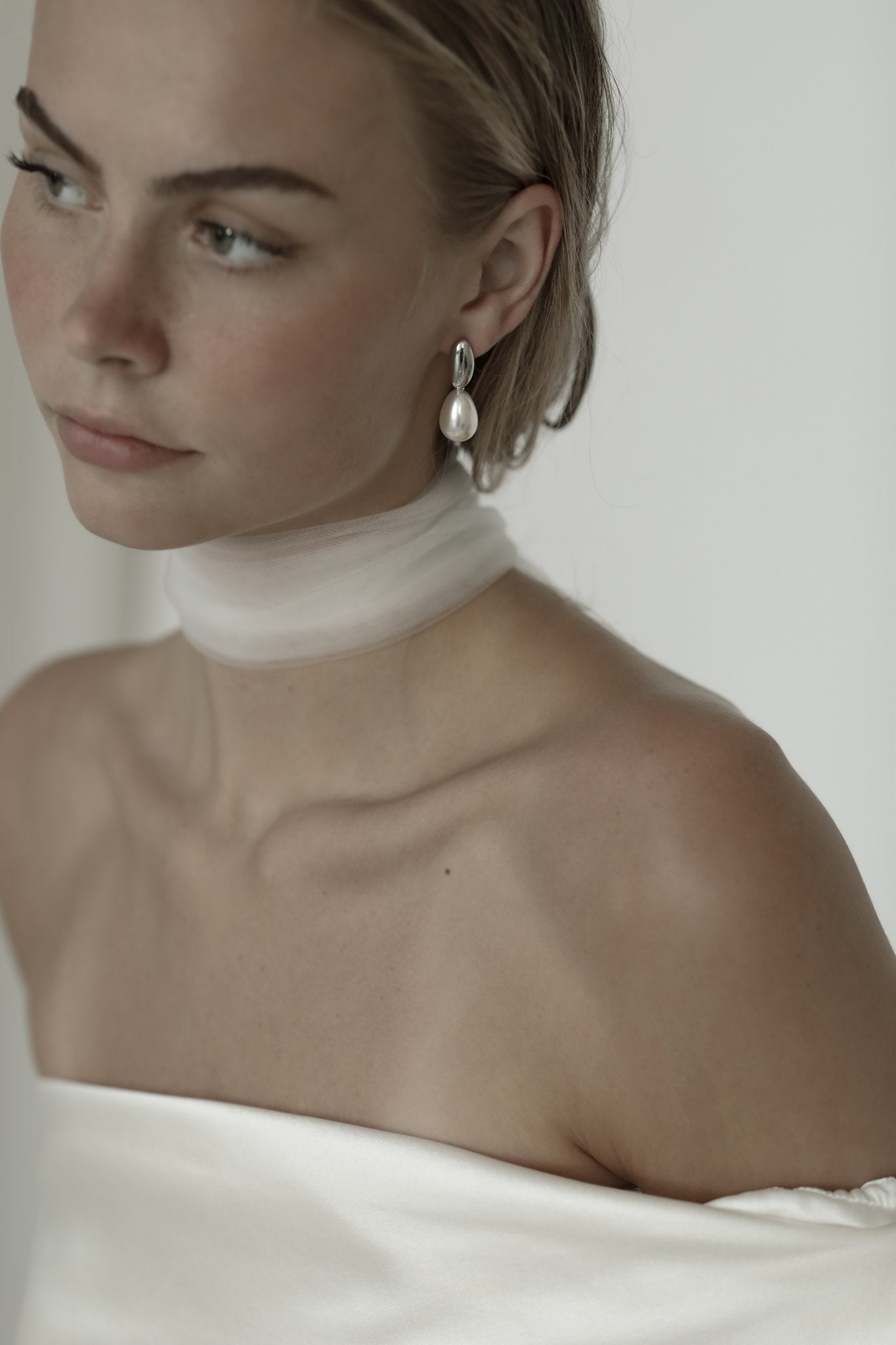 Blonde bride wearing silver pearl drop earrings by AB Ellie with a strapless wedding dress.