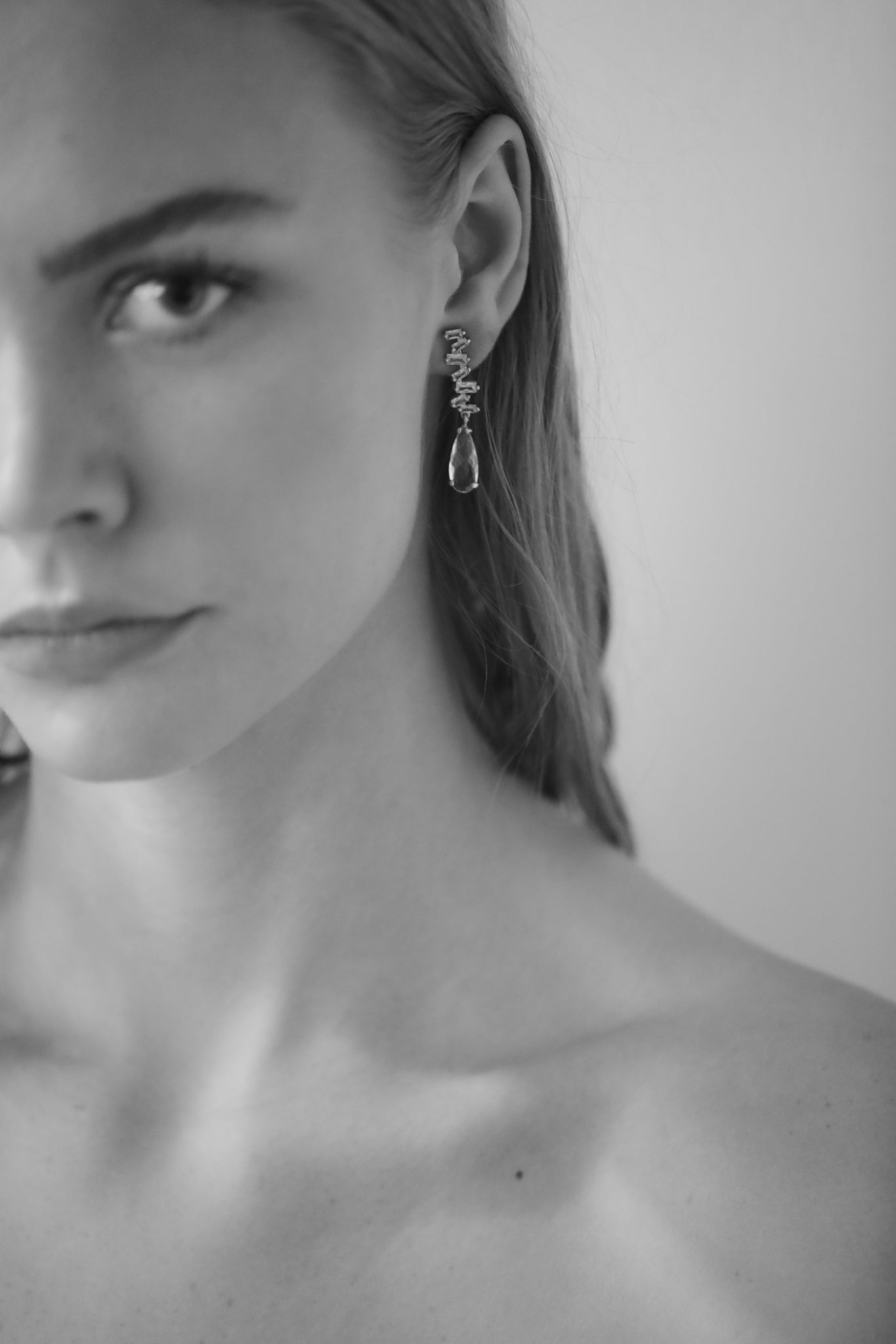 Black and white photo of brunette bride wearing a stacked crystal drop earring