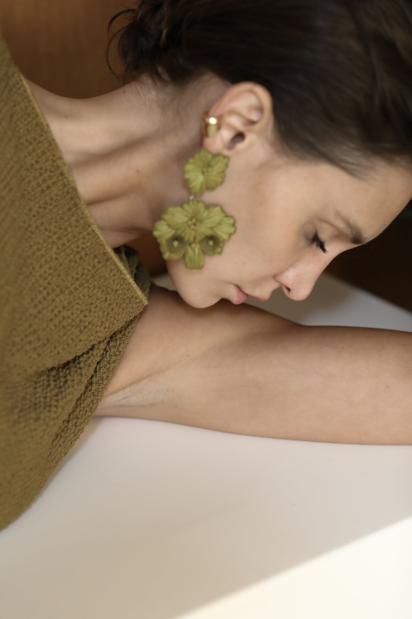 Brunette side profile wearing the Stevie floral statement earrings in Olive color by AB Ellie