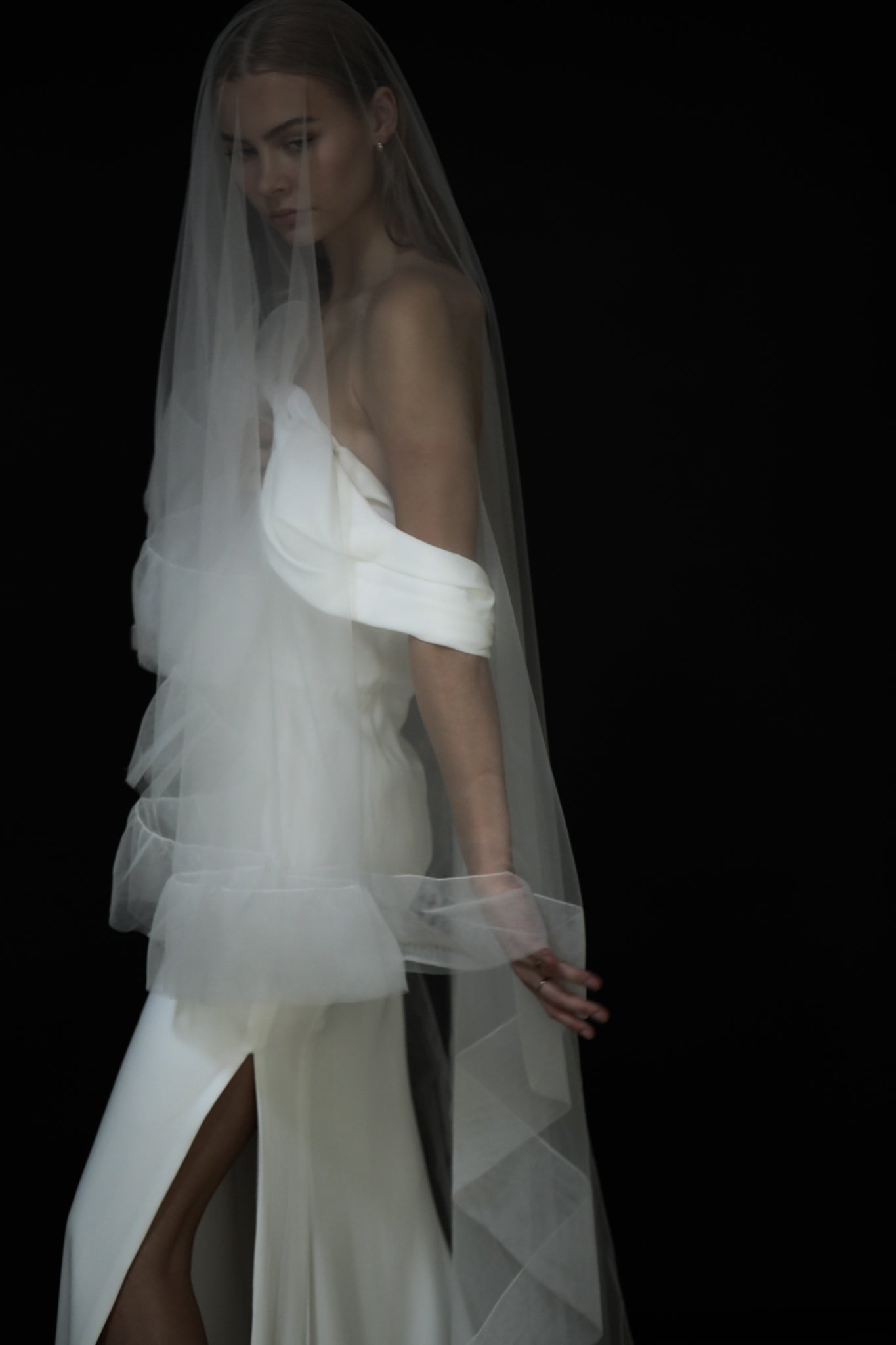 A bride wearing a tulle edge wedding veil with a subtle ruffle detail, flowing gently in the air.