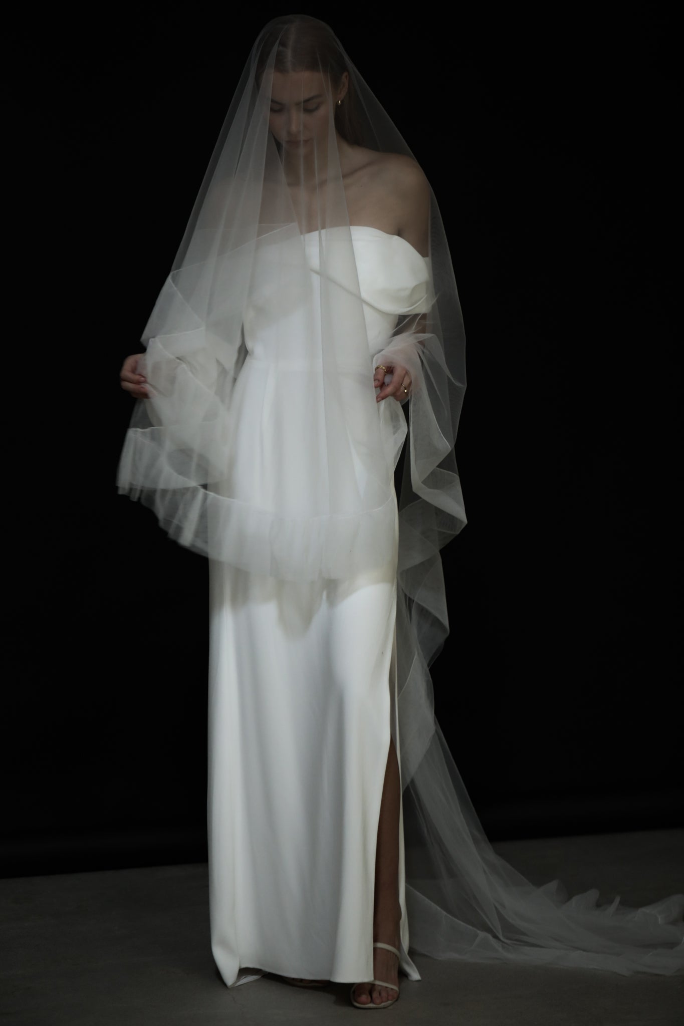 Bride wearing tulle edged wedding veil on a black background