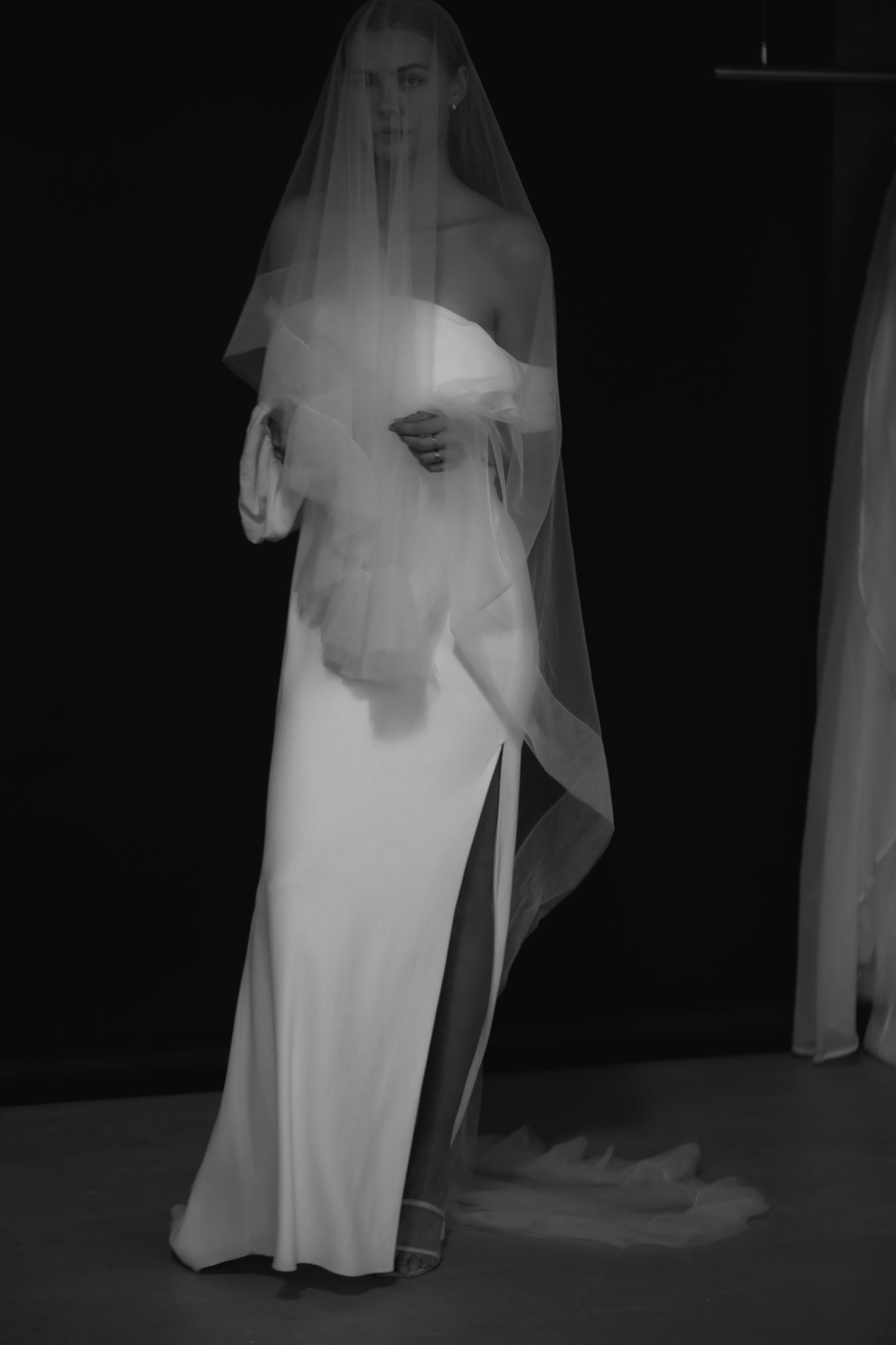 Bride wearing tulle edged wedding veil with blusher on a black background