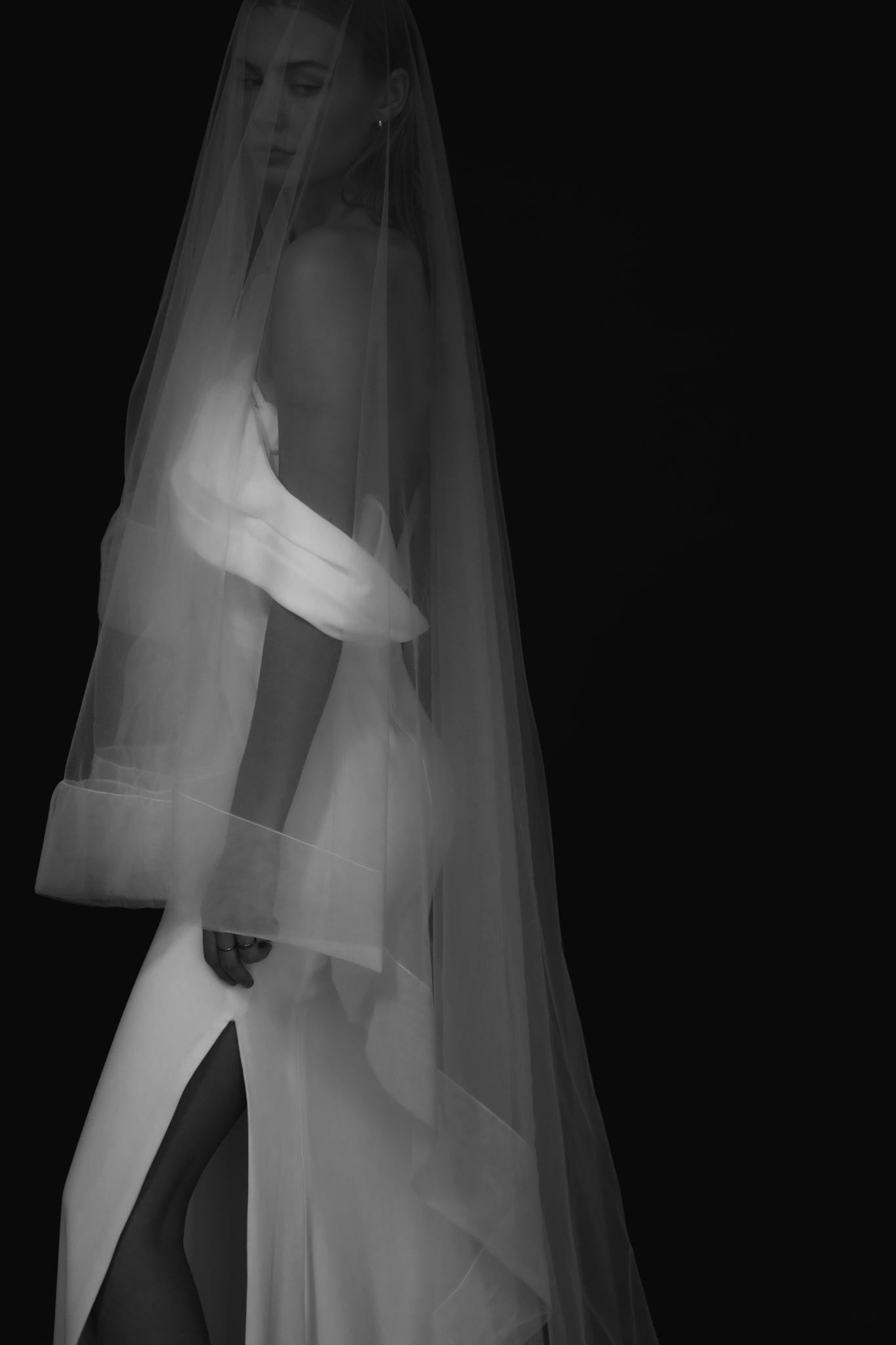 Side profile of bride wearing tulle edge wedding veil with blusher on black background by A.B. Ellie