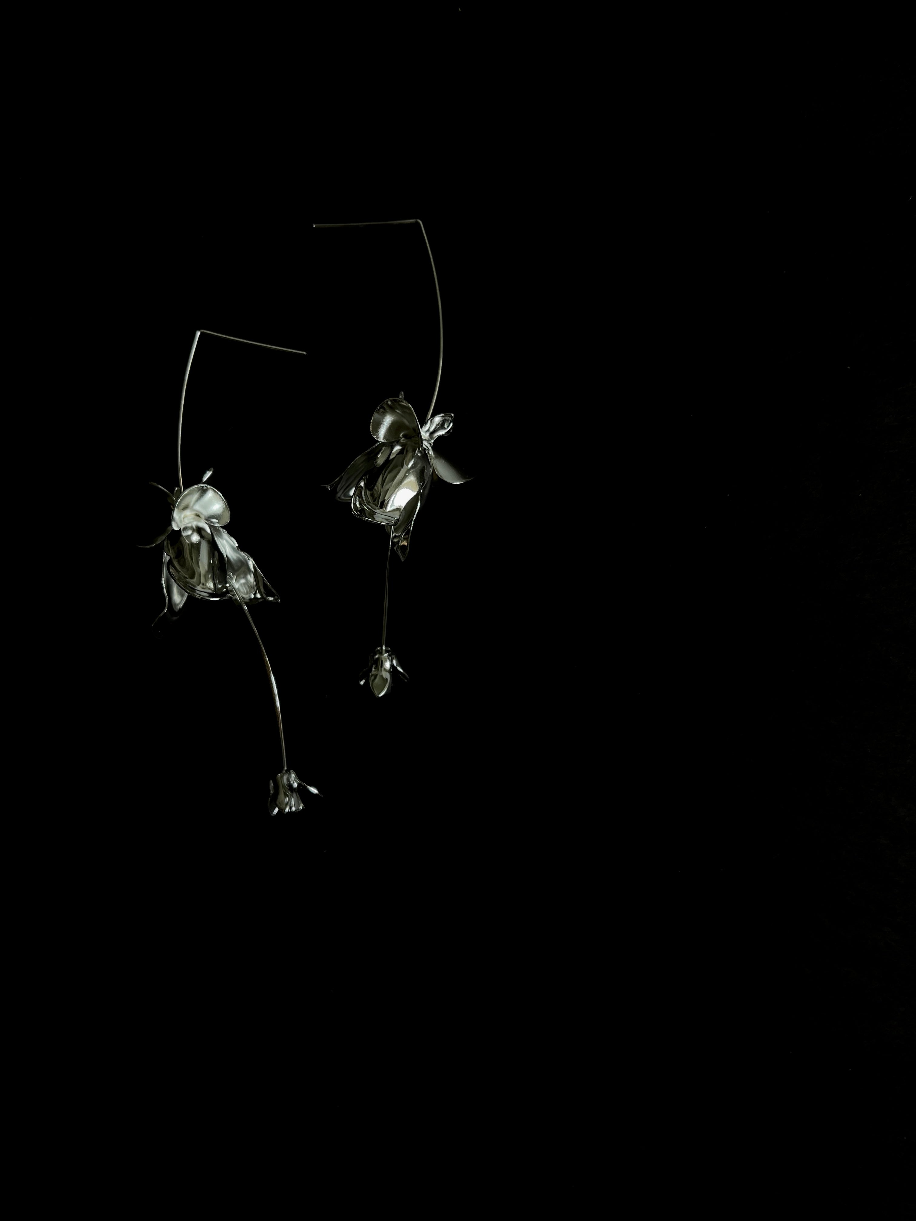 Stunning silver floral drop delicate earrings shot on a dramatic black background.