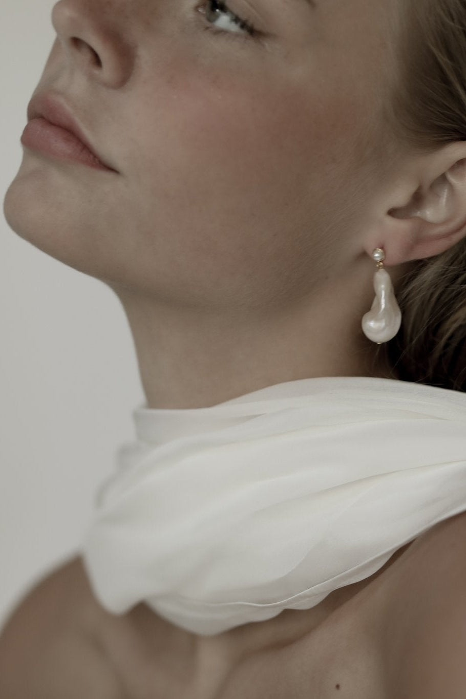 Close up photo of bride wearing the startement baroque pearl drop earrings by AB Ellie with silk neck scarf