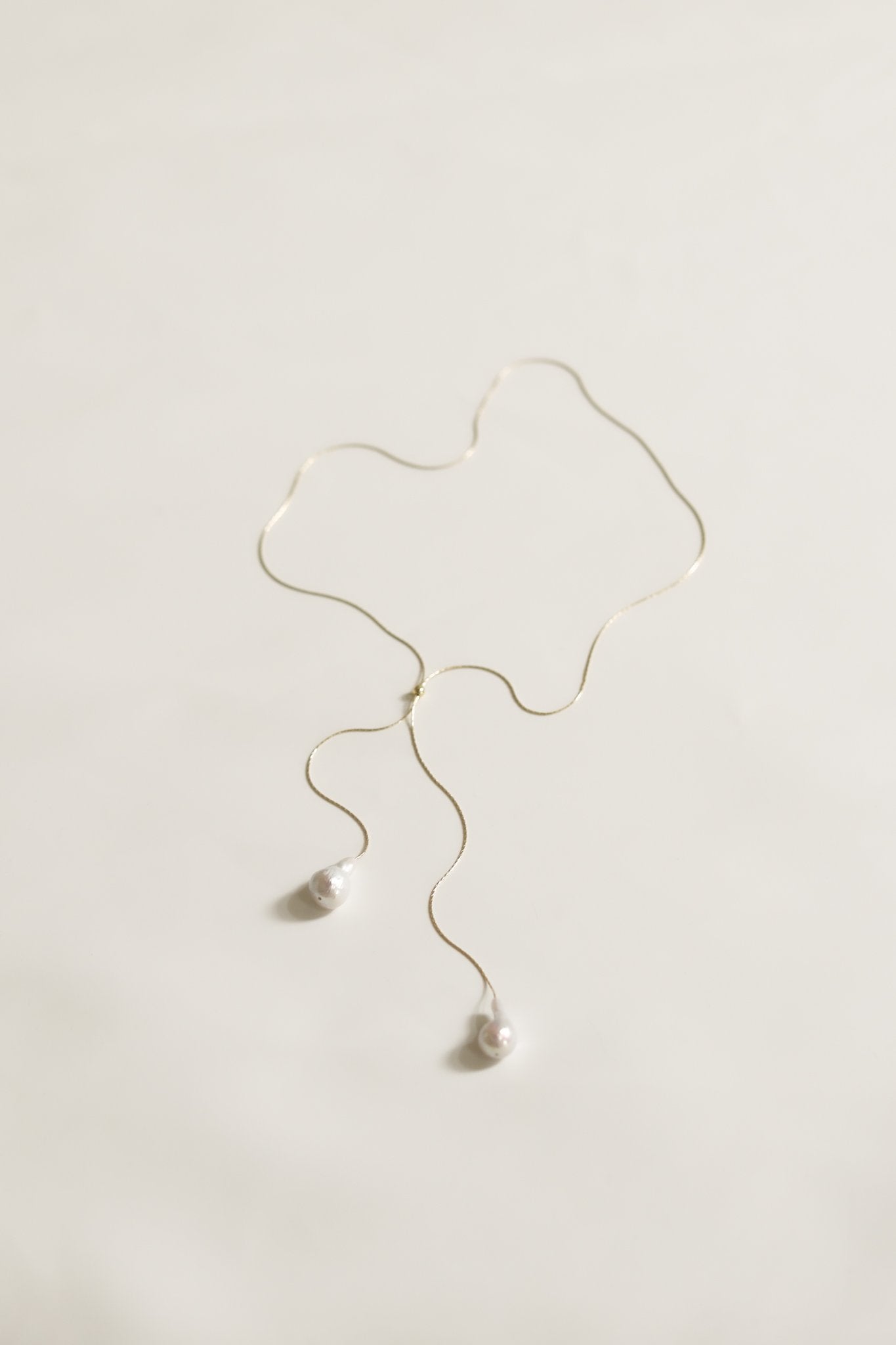 Flat view of the baroque pearl lariat necklace with gold strand on white background