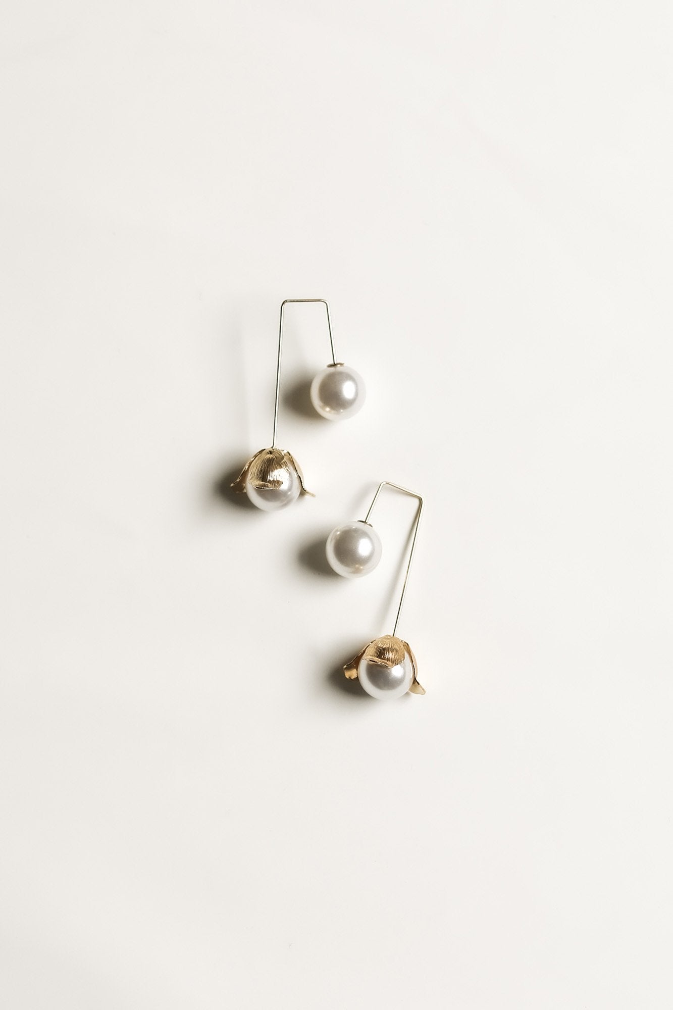 Flat view of a pair of the Bardot pearl drop earrings by AB Ellie on a white background.