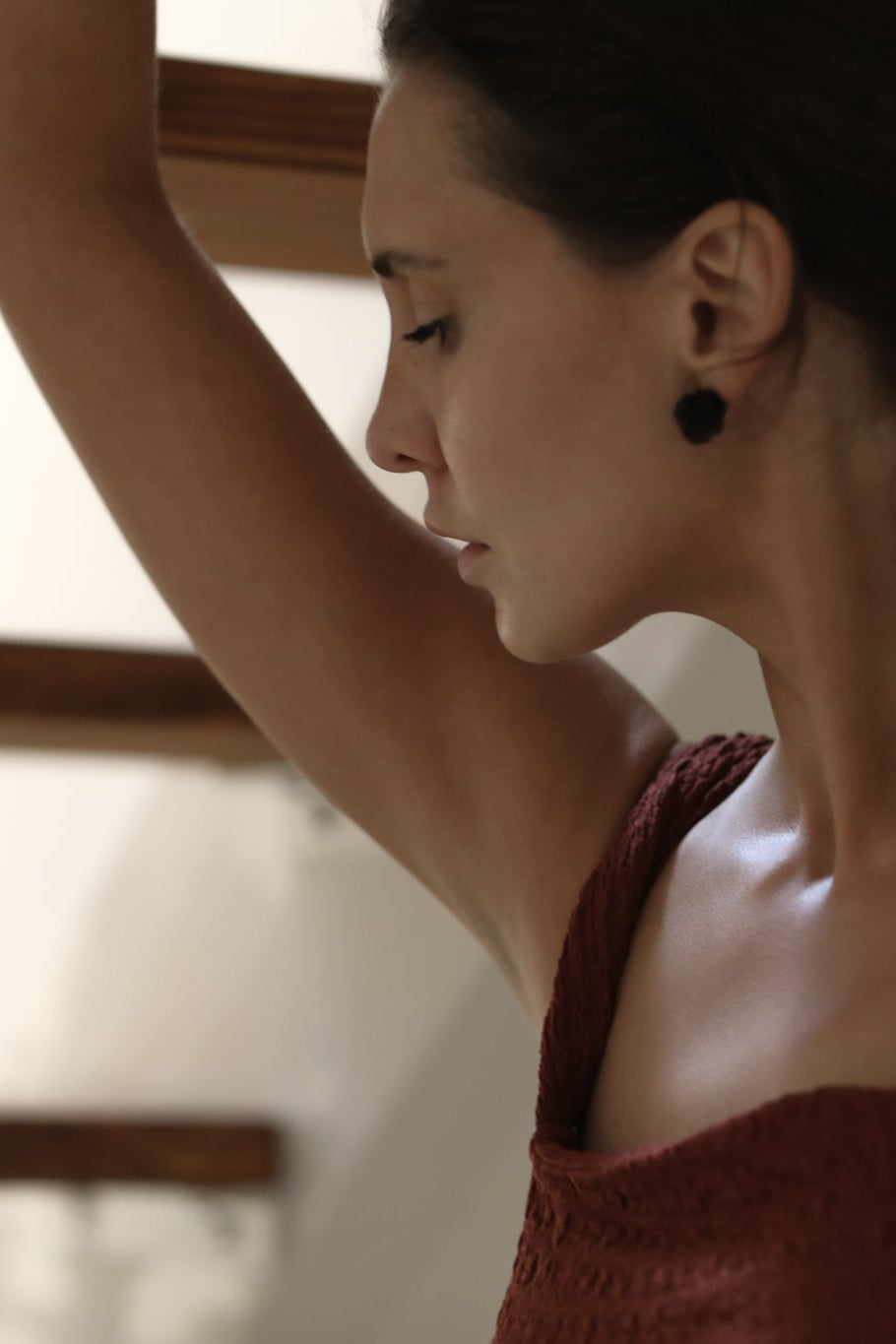 Brunette wearing burgundy dress paired with black celine stud earrings by A.B. Ellie 