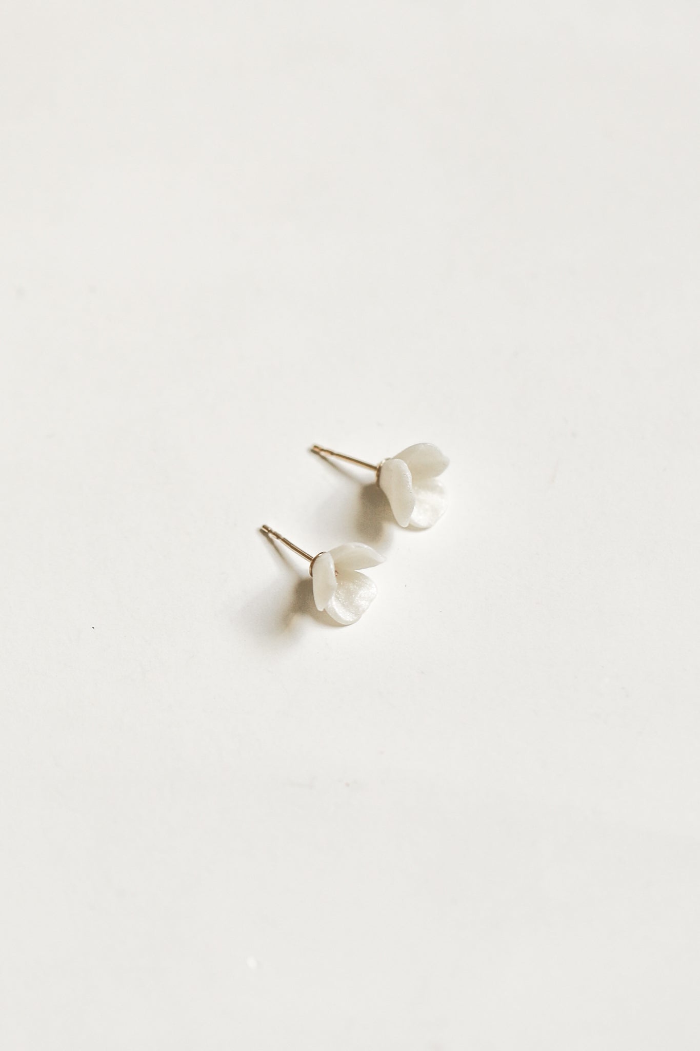 The delicate A.B. Ellie Blossom two in one strand style is shown without the strand attached. The minimal ivory flower stud with gold plated post is lightweight option for rehearsal dinner or honeymoon.