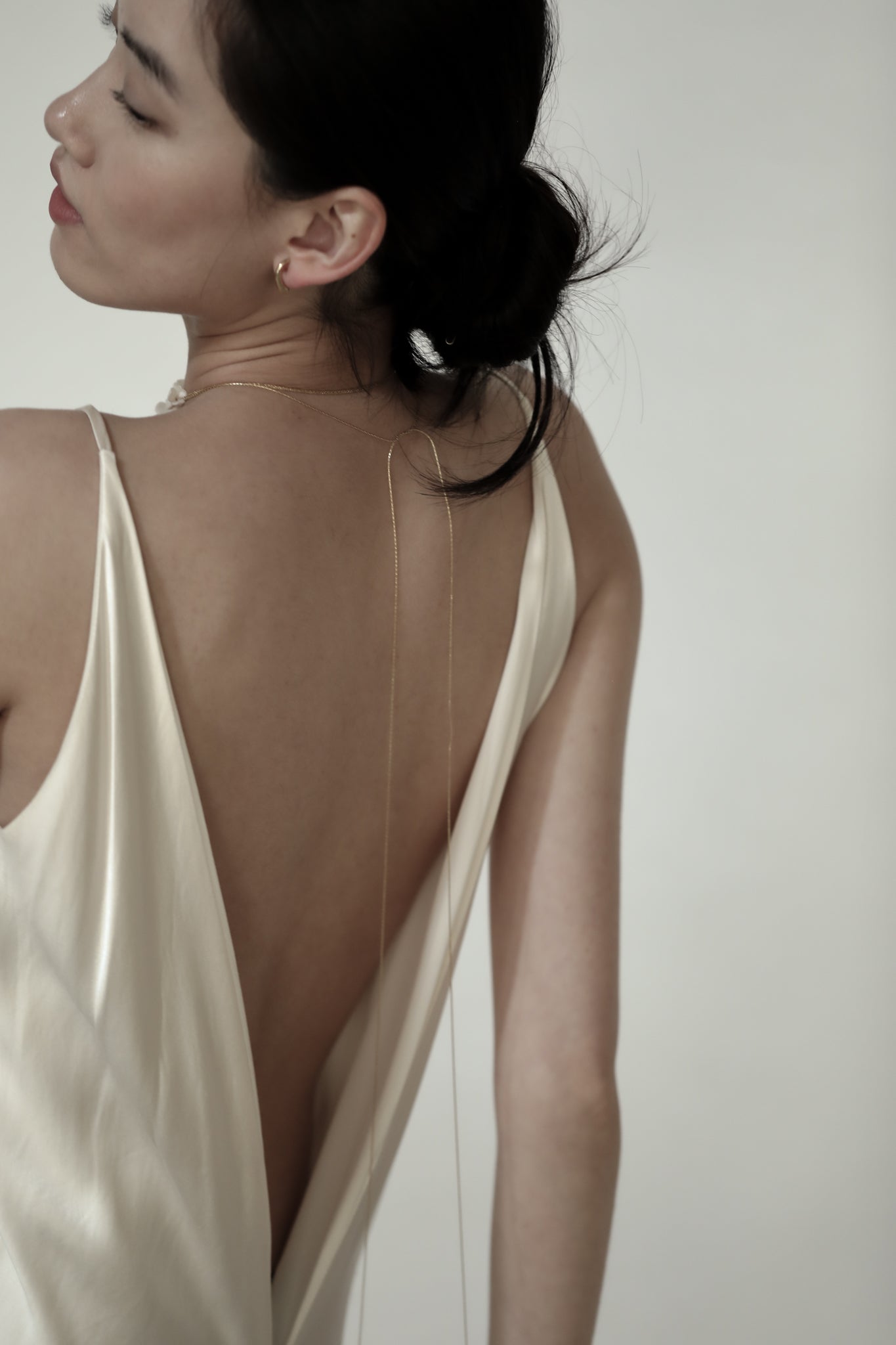 Bride wearing a open back dress with the blossom wrap necklace against a white background 