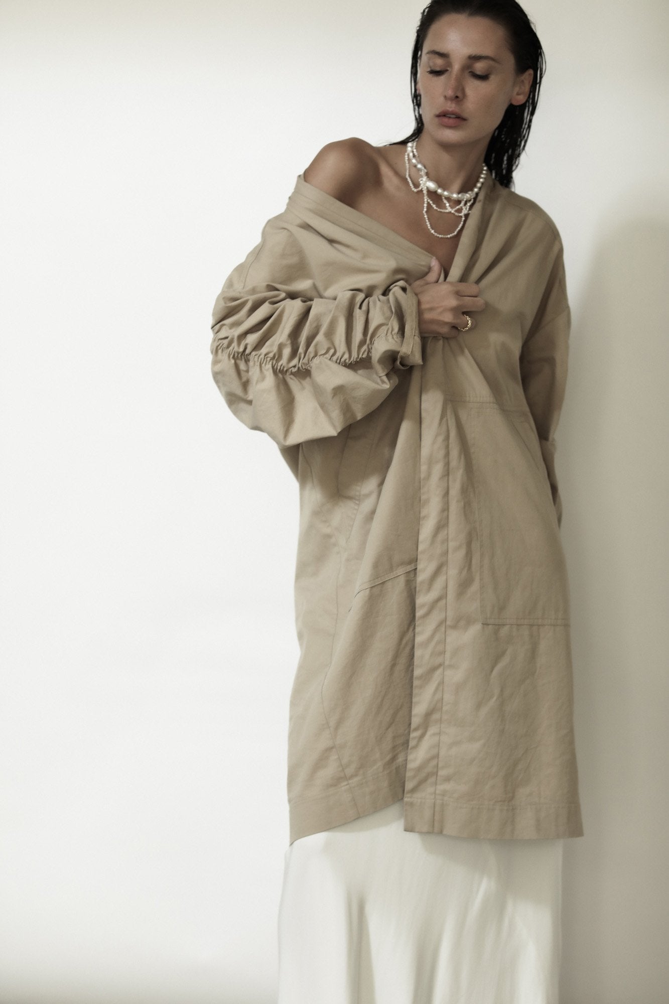 Brunette wearing the cascading freshwater pearl necklace by AB Ellie pared with oversized tan coat