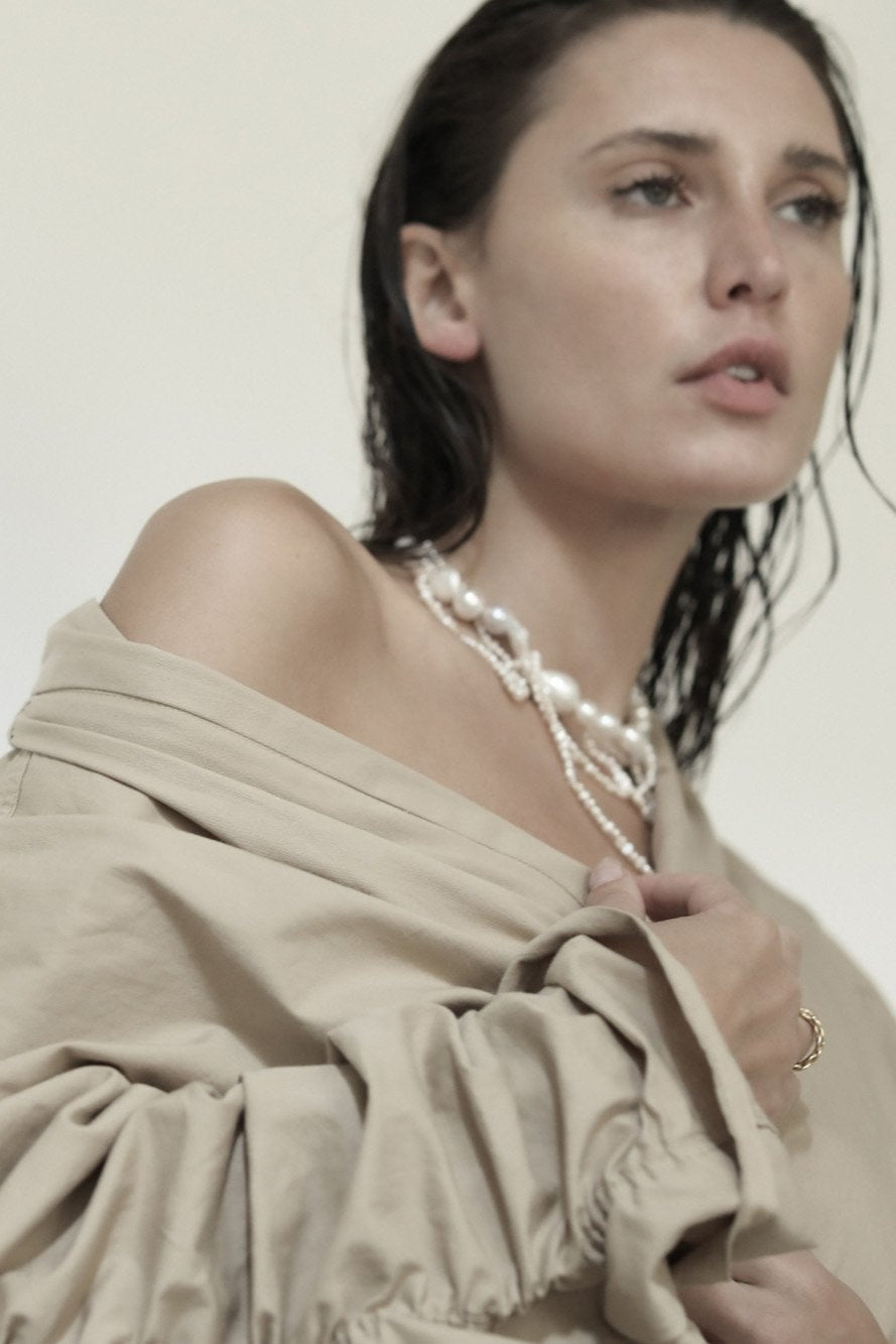 Brunette wearing the cascading freshwater pearl choker necklace by AB Ellie paired with a tan coat