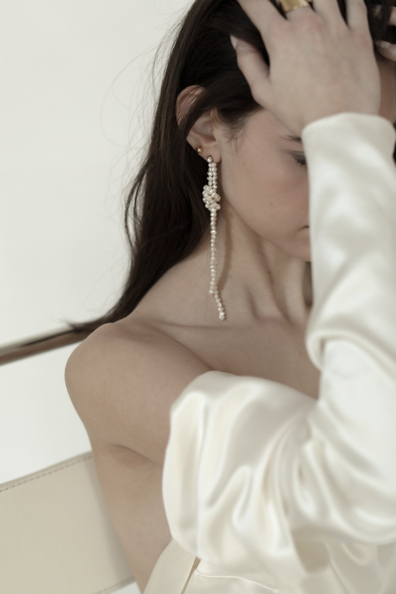 Photo of brunette bride wearing the knotted freshwater pearl strand earrings by AB Elle with off shoulder dress.