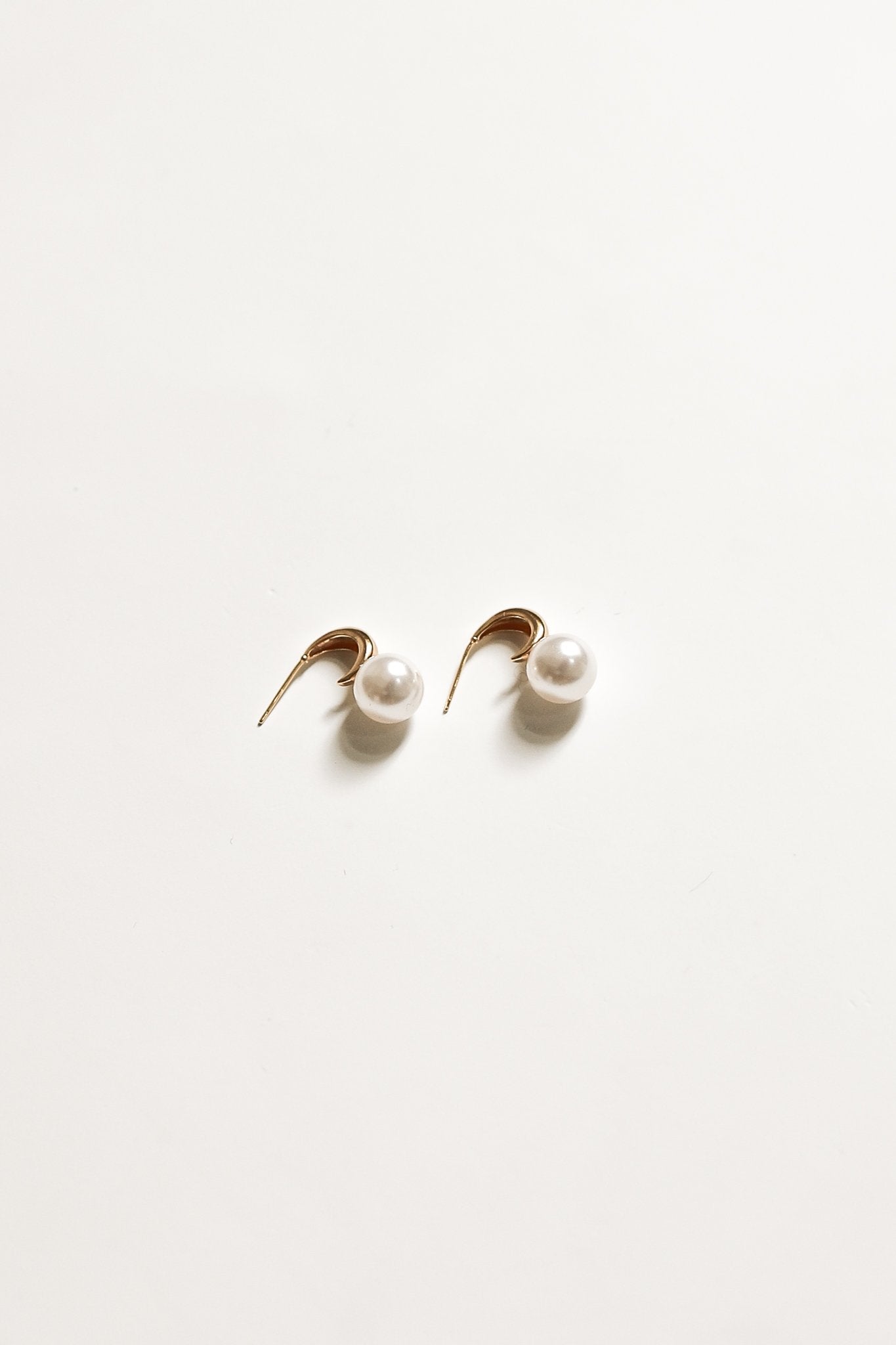 Flat side view of gold crescent hoop pearl earrings by AB Ellie on white background