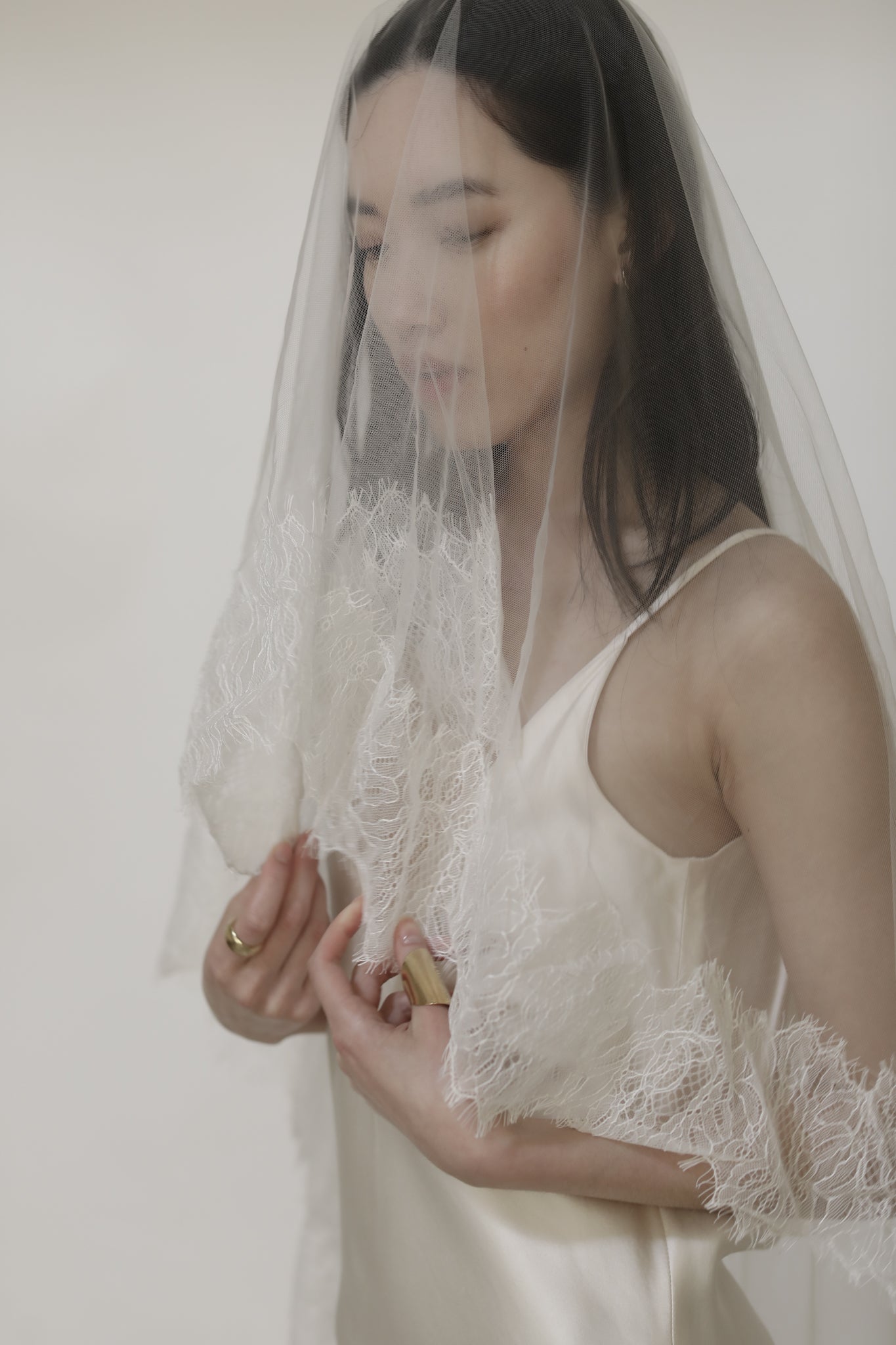 Front view of bride with dark hair wearing mantilla wedding veil with lace blusher