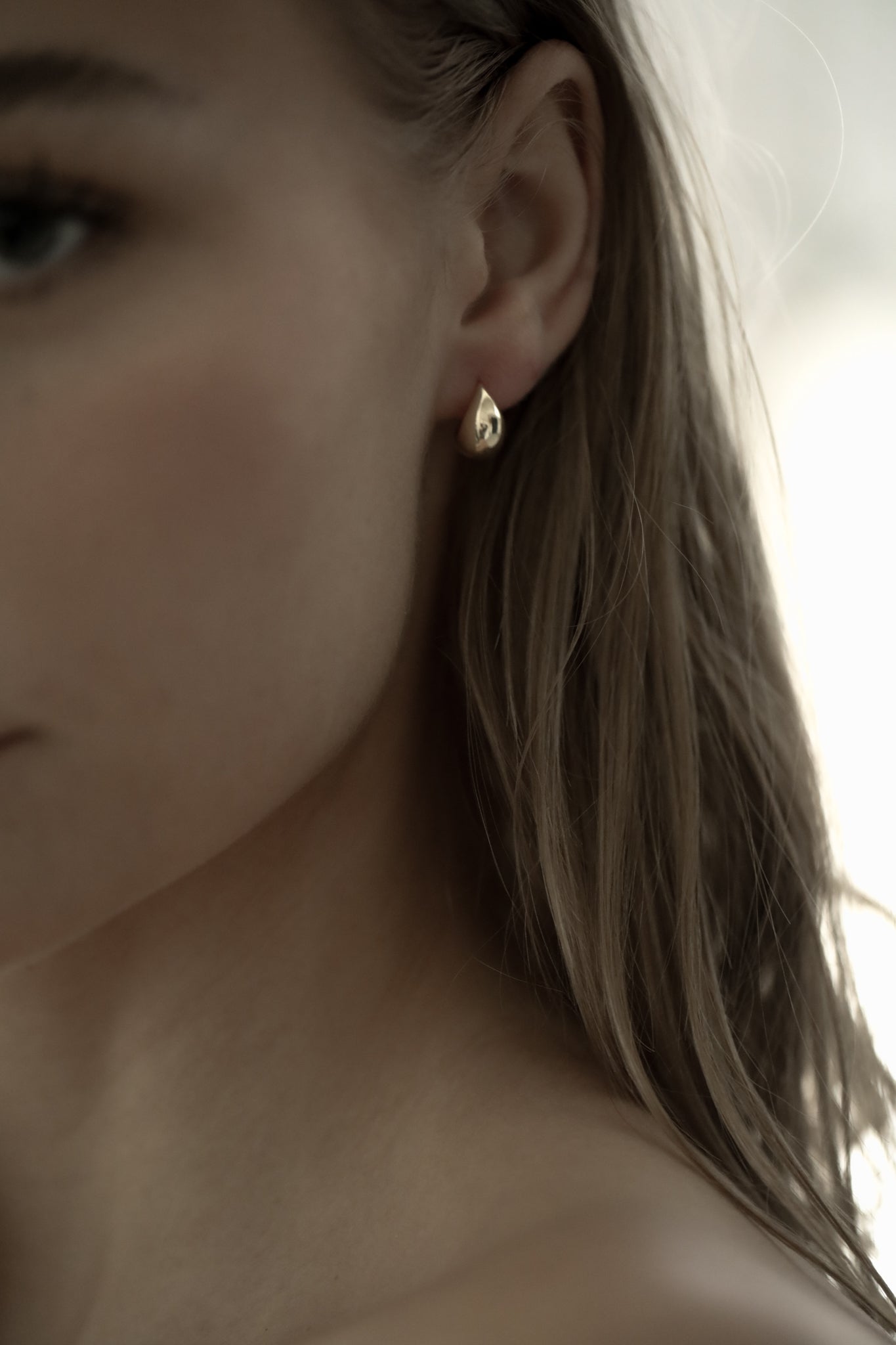 Photo of brunette woman wearing the micro orb gold earring by AB Ellie